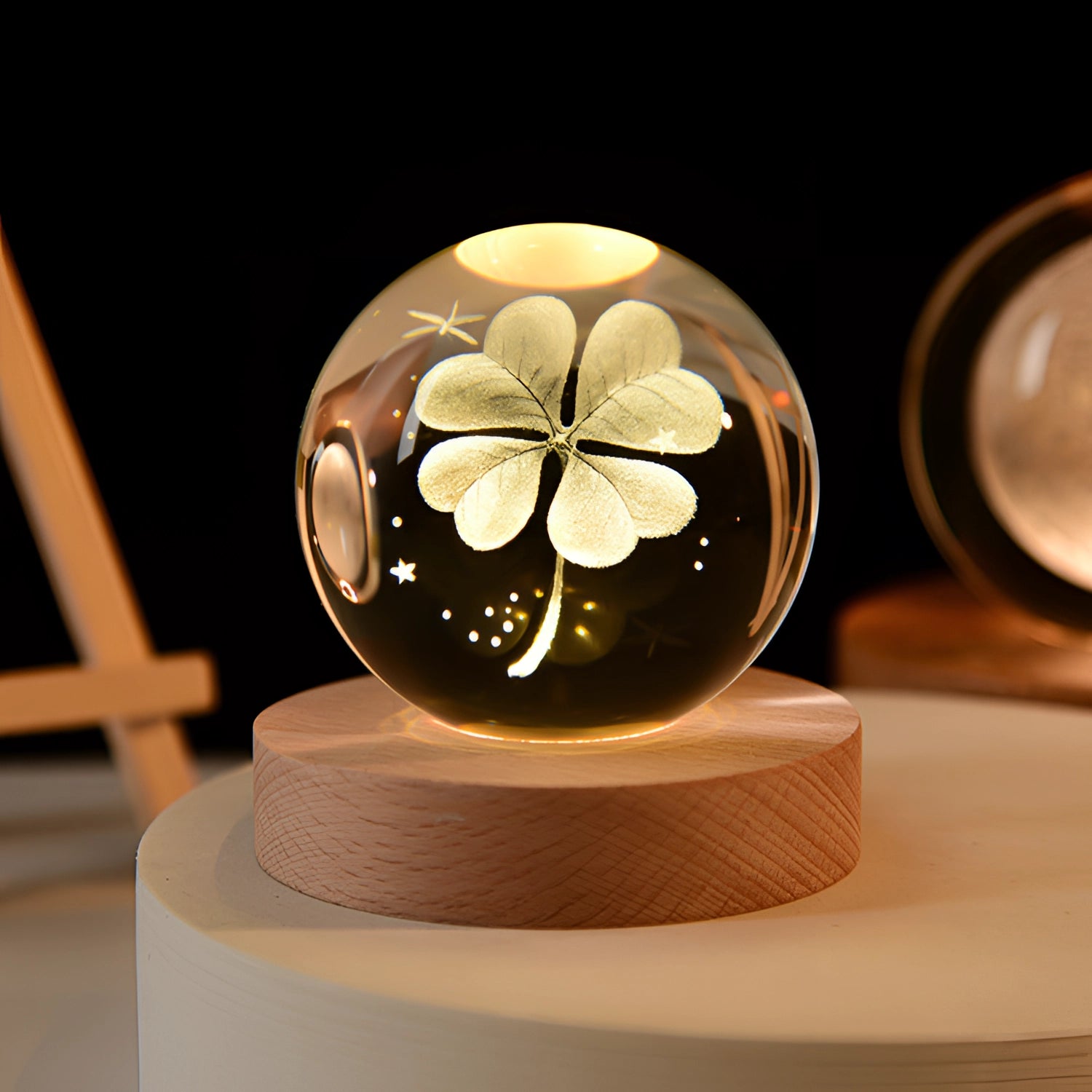 3D Crystal Ball LED Light with laser engraved galaxy and planetary designs on a wooden base, featuring a cloverleaf pattern inside a clear 8 cm sphere.