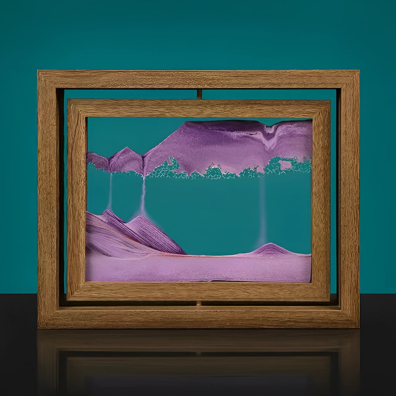 3D kinetic sand art picture frame in aqua blue with rotating purple sand, displayed on a desk. The frame is rectangular and crafted with a wooden border, showcasing a blend of pink and magenta hues swirling creatively, capturing the essence of visual and creative arts.