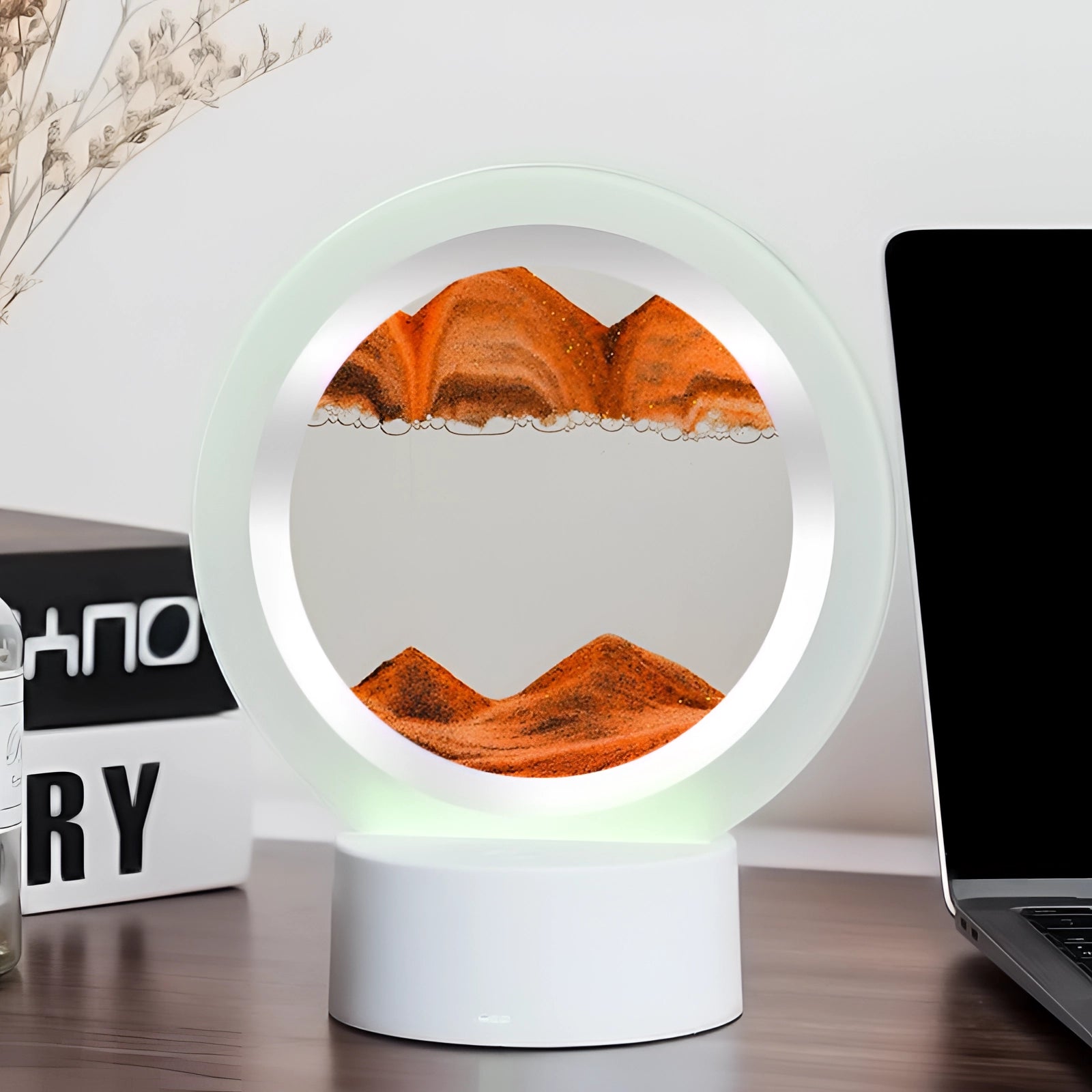 Orange 3D LED Sand Art Night Light Lamp with a Resin Mountain Design, placed on a wooden surface, providing a warm ambient glow in an interior setting.