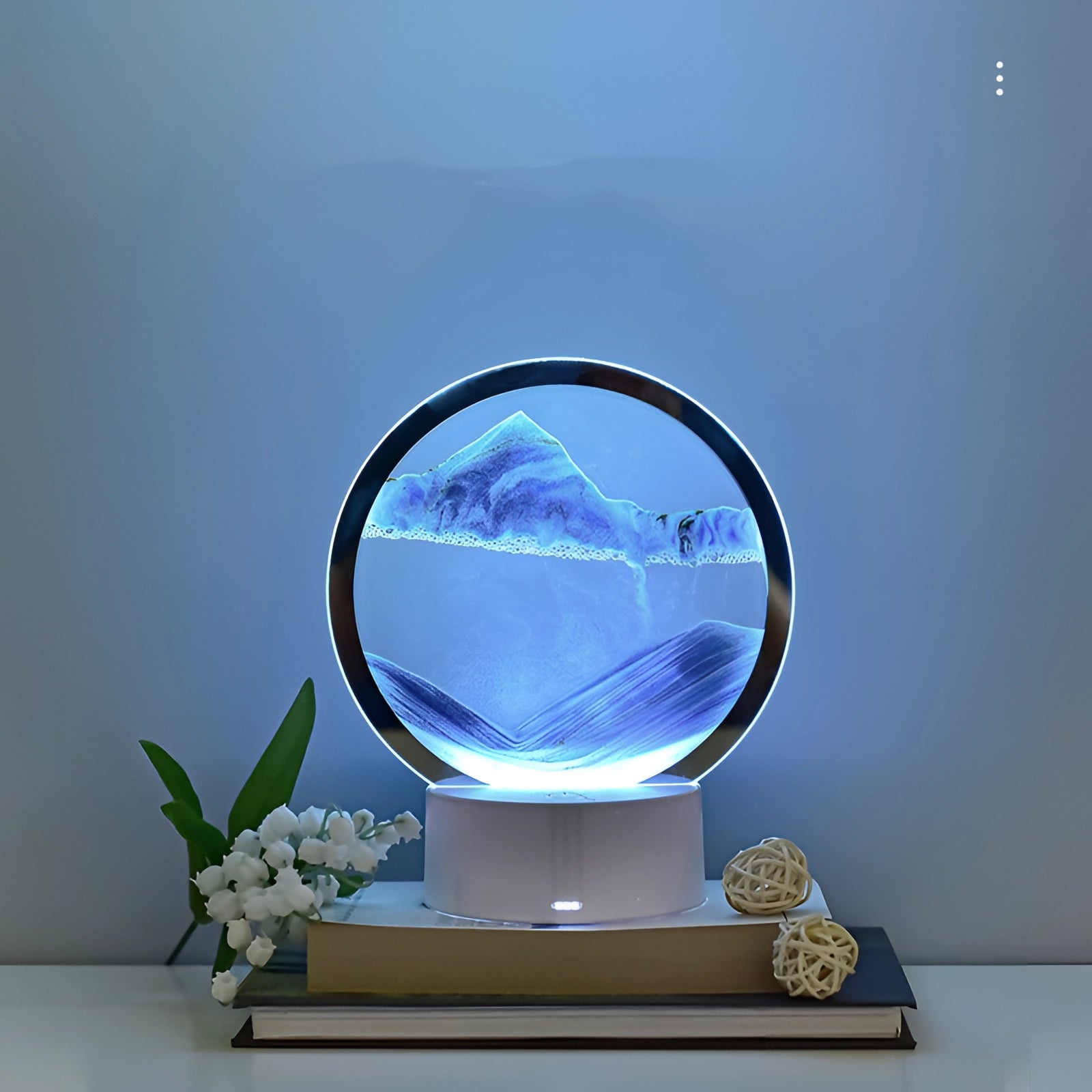 3D LED Sand Art Night Light Lamp featuring a resin mountain design, illuminated with electric blue lighting and set in a circular frame, resting on a table.