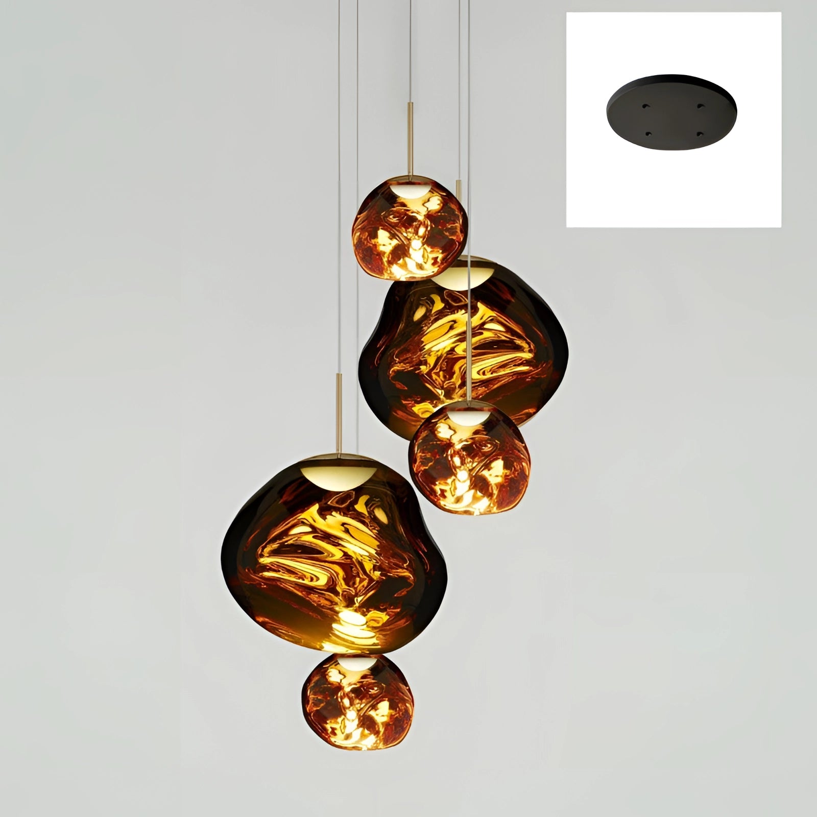 Amber glass triple pendant light fixture with five heads in gold, featuring three smaller and two larger circular glass shades, hanging from a modern copper ceiling mount.