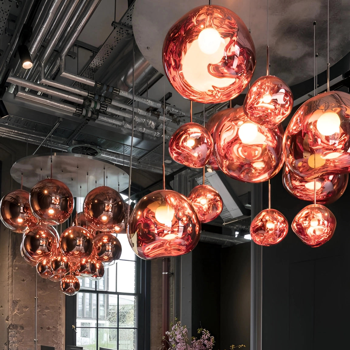 Amber glass triple pendant light fixture with modern copper accents, suspended from the ceiling, illuminating a stylish interior space with warm orange and amber tints, serving as both a functional light source and a decorative ornament.