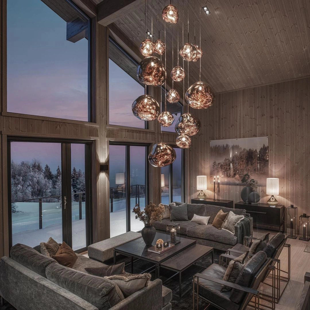Modern copper ceiling lamp featuring an amber glass triple pendant light fixture, elegantly illuminating a stylishly designed living room with contemporary furniture and decor elements.