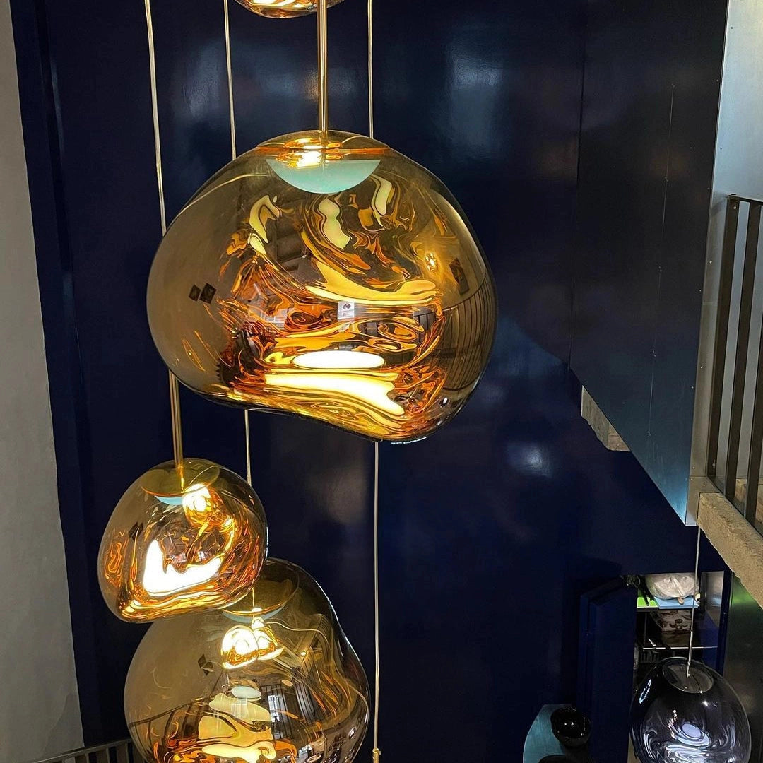 Amber glass triple pendant light fixture with modern copper accents, featuring three circular glass shades hanging from a metal ceiling mount, showcasing a warm, elegant glow with visible light bulbs inside each pendant.