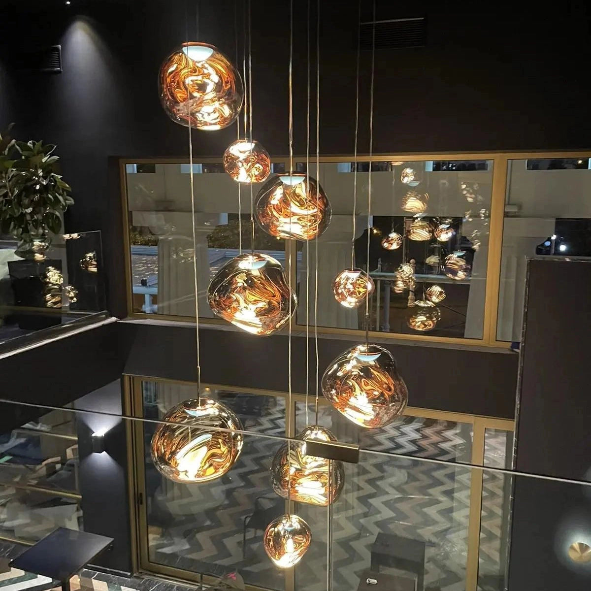 Amber glass triple pendant light fixture with modern copper design, hanging from a ceiling, creating an elegant and artistic ambiance in an interior space.