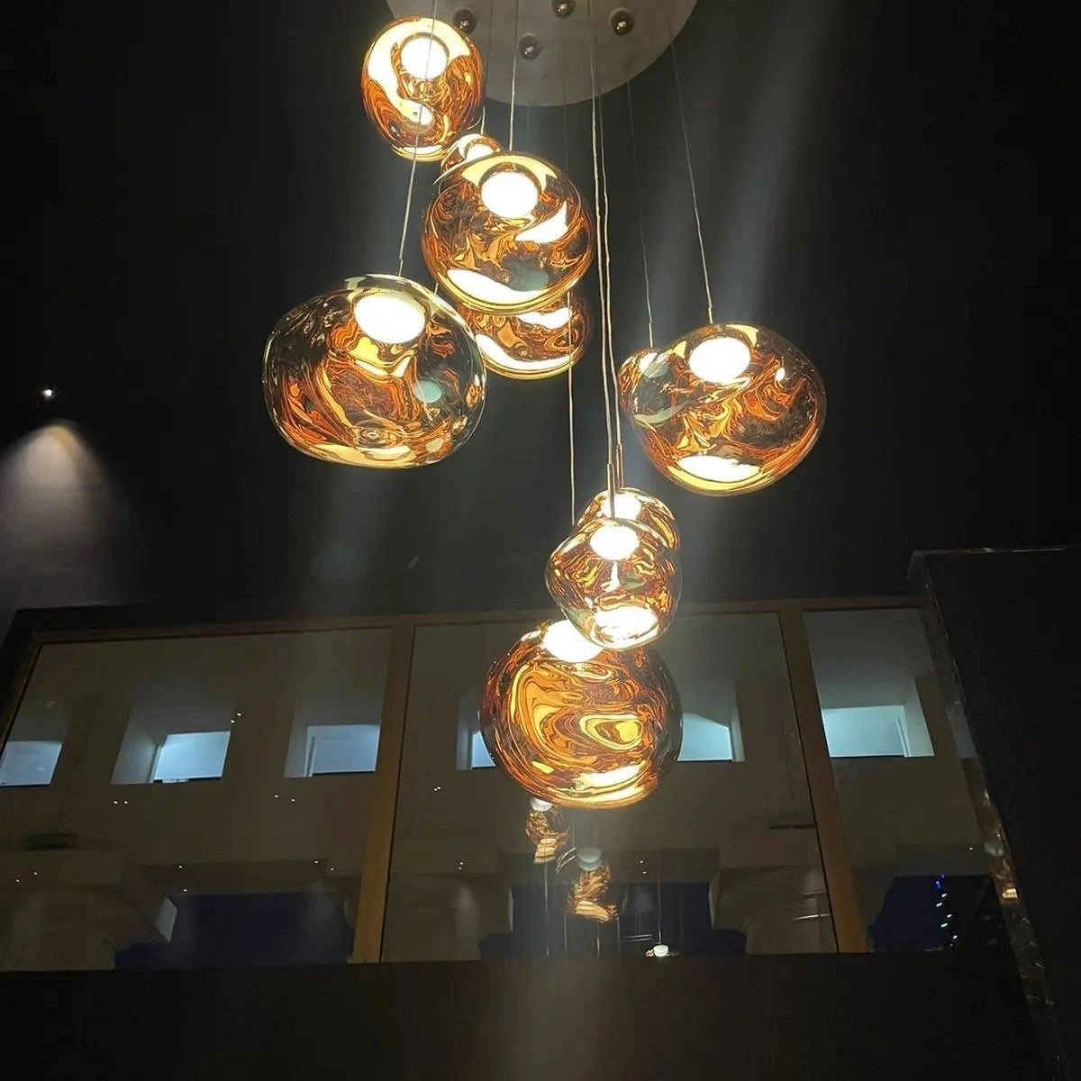 Amber glass triple pendant light fixture featuring a modern copper design, showcasing three circular glass shades suspended from the ceiling, each encasing a light bulb to create a warm, ambient glow.