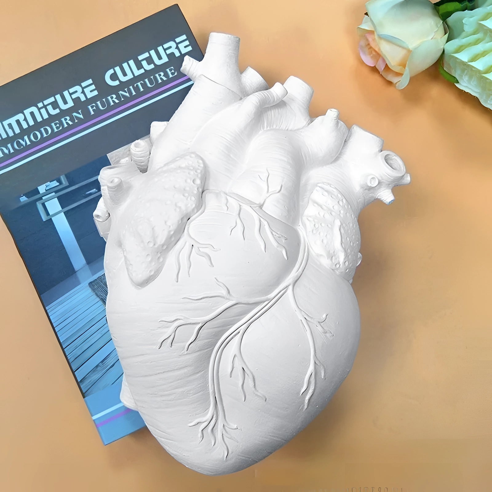 Artistic anatomical heart-shaped vase used as a flower planter, featuring intricate details and a creative design, resembling a human heart with visible ventricles and aorta, crafted from clay.
