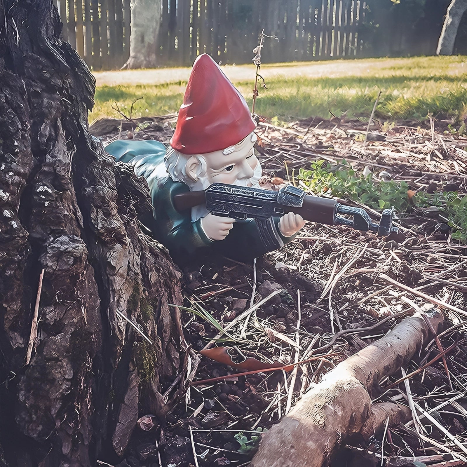 Armed Warrior Garden Gnome Statue featuring a military-themed design, dressed in camouflage and holding an AK-47, set on a grassy lawn amidst nature.