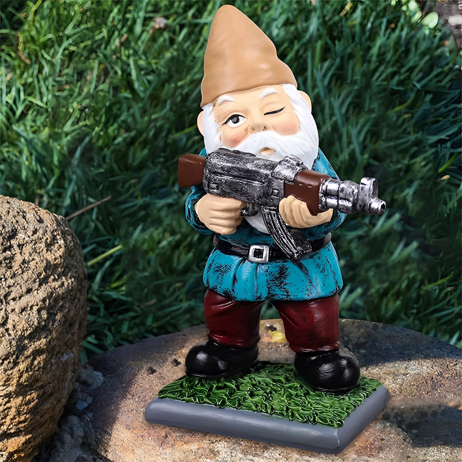 Armed Warrior Garden Gnome Statue depicting a military-themed garden gnome holding an AK-47, set against a lush outdoor background with grass and trees, designed as a decorative lawn ornament.