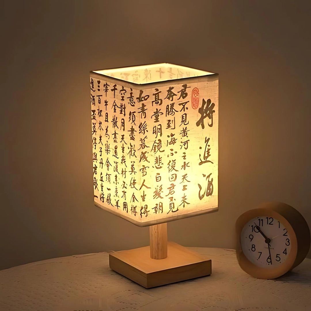 Asian-inspired wooden table lamp with a rectangular base, featuring a parchment lampshade, blending traditional craftsmanship with modern aesthetics.