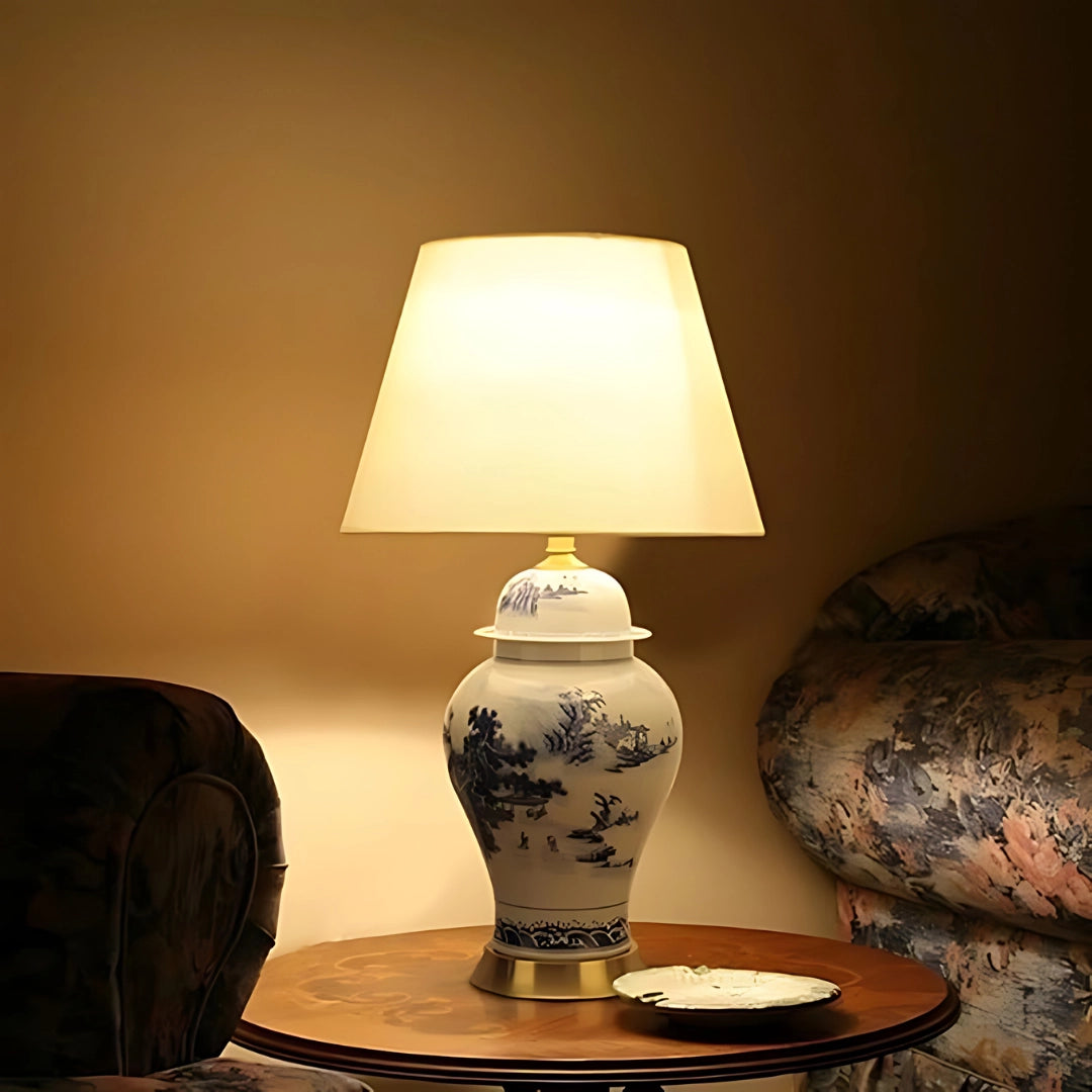 Blue and white porcelain table lamp with intricate Chinese ceramic design, featuring a warm white light, placed on a wooden table within a stylishly designed interior space.