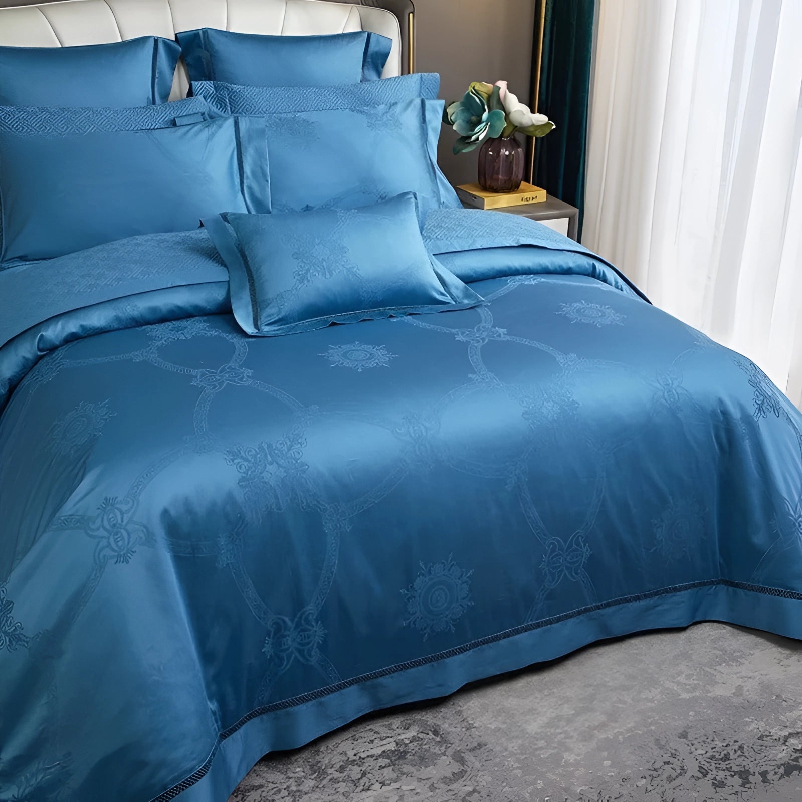 Blue king size silk bedsheet set with a luxurious and wrinkle-free finish on a neatly made bed, in a well-designed bedroom interior featuring hardwood flooring, blue curtains, and a potted plant.
