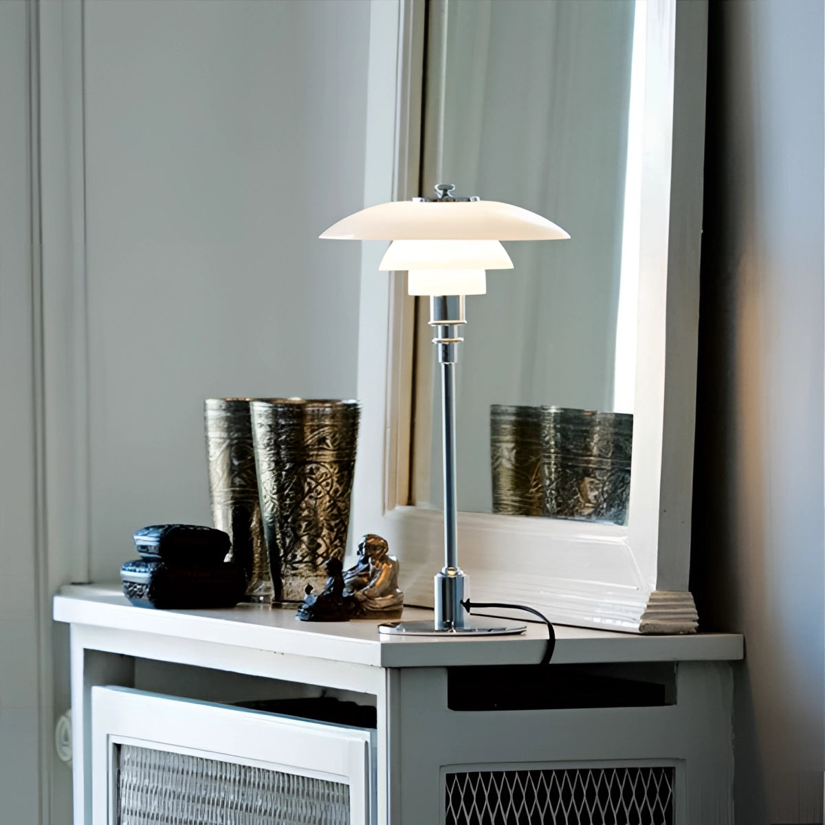 Brass table lamp with opal glass shade placed on a wooden shelf in a minimalist interior design setting with grey walls.