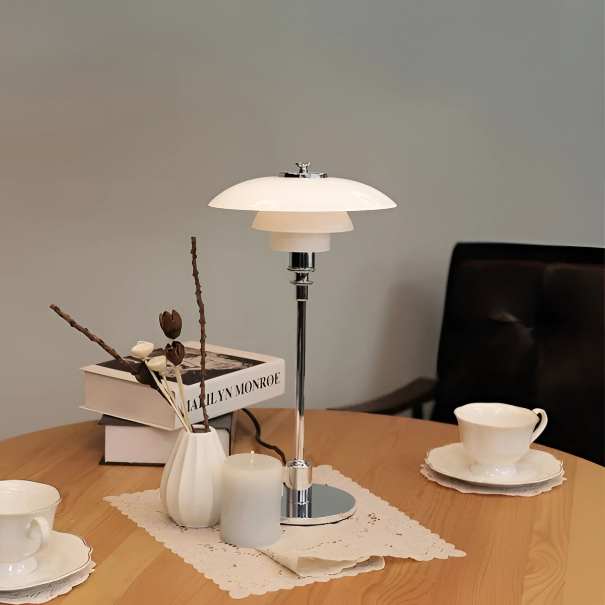 Brass table lamp with opal glass shade, featuring a minimalist design, placed on a wooden table in a modern interior setting.
