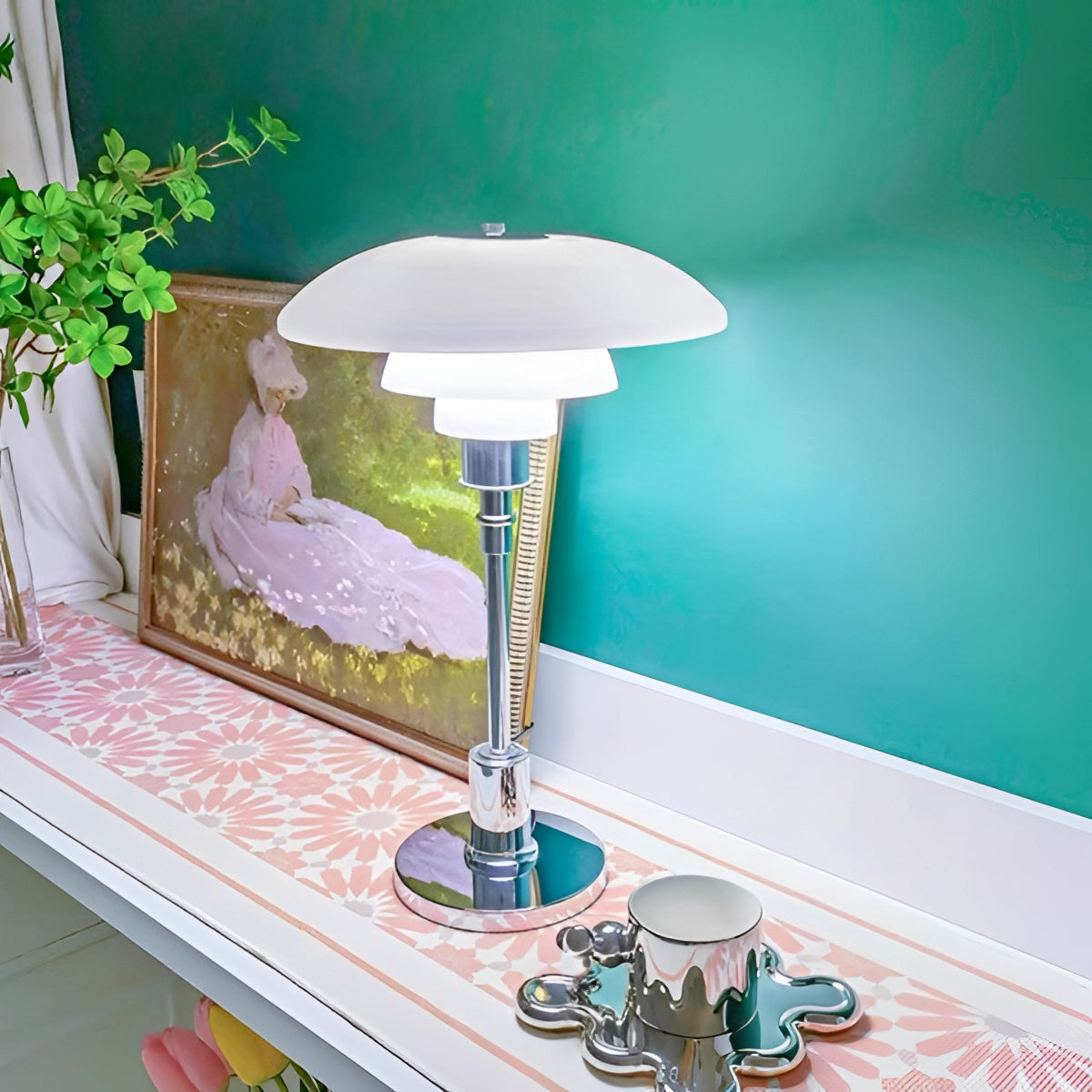 Brass table lamp with opal glass shade on a wooden table, surrounded by a potted plant and a coffee cup, in a minimalist interior setting.