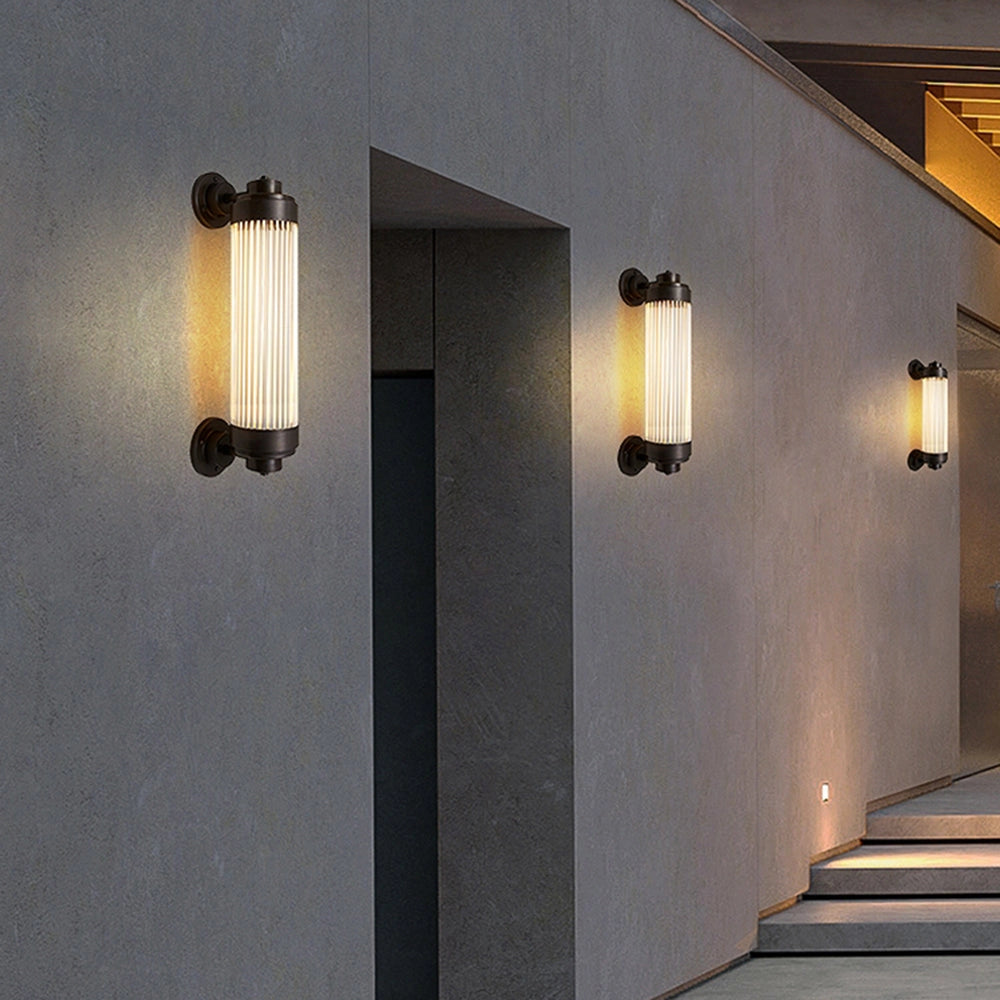 Bronze vintage glass tube wall sconce mounted on a wooden wall, featuring industrial design elements suitable for a bathroom setting.