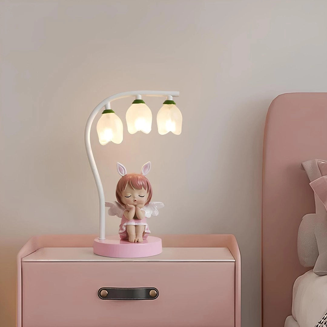 Cartoon bee LED night light in the shape of a cute bee with pink accents, placed on a wooden surface with a white and magenta color scheme. The lamp is positioned near a drawer and wall stickers, making it an ideal addition to a child's room interior design.