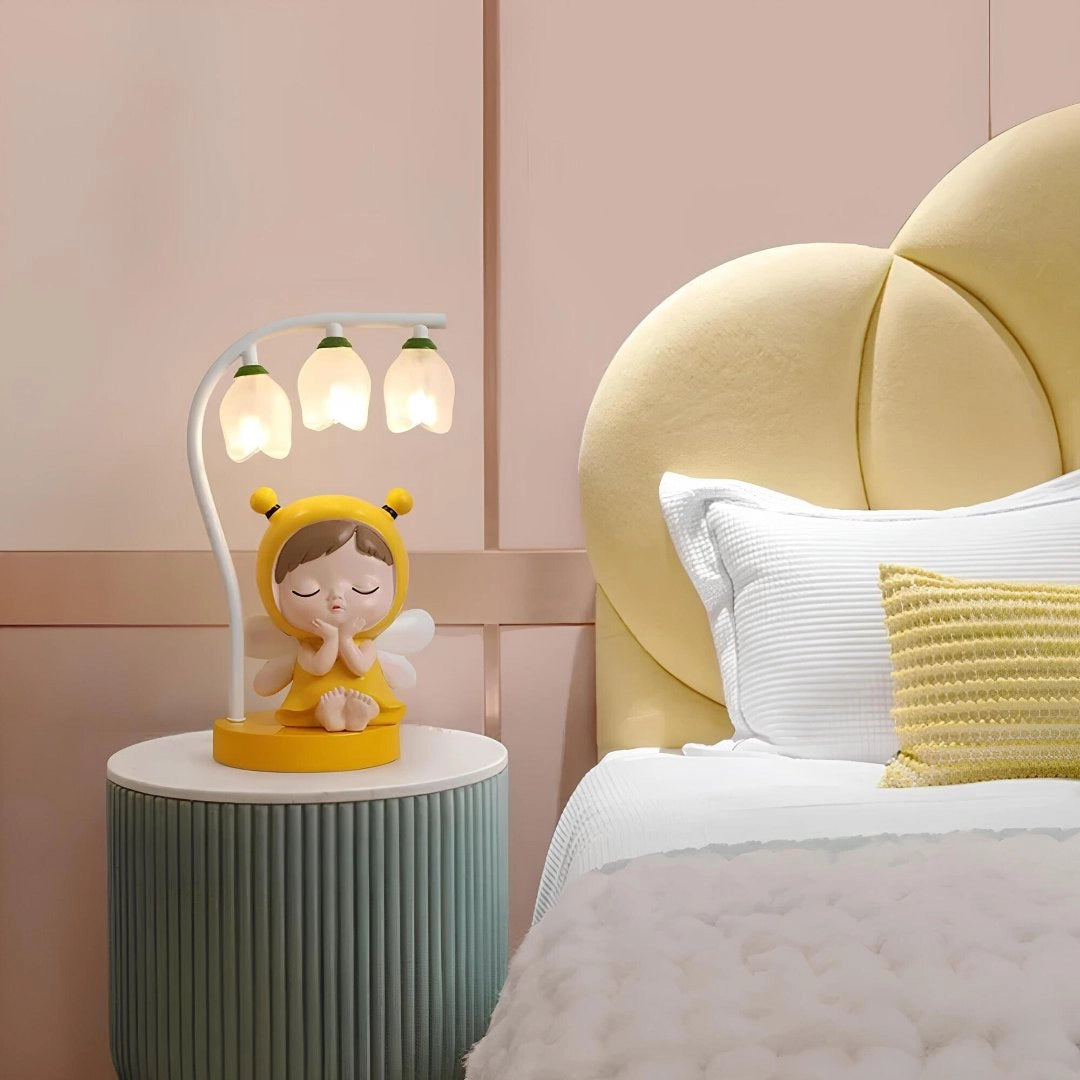 Cartoon bee LED night light on a wooden table, designed as a cute, adjustable lamp ideal for children's rooms, surrounded by soft pillows, enhancing interior decoration and providing comfort.
