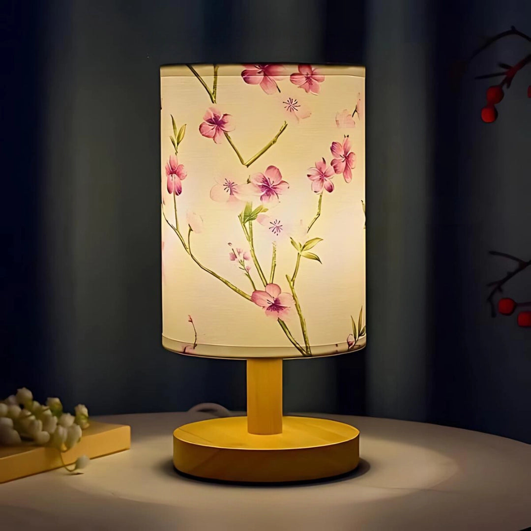 Cherry blossom table lamp with illuminated sakura flowers on a wooden base, placed on a table, showcasing an artistic and elegant interior design element.