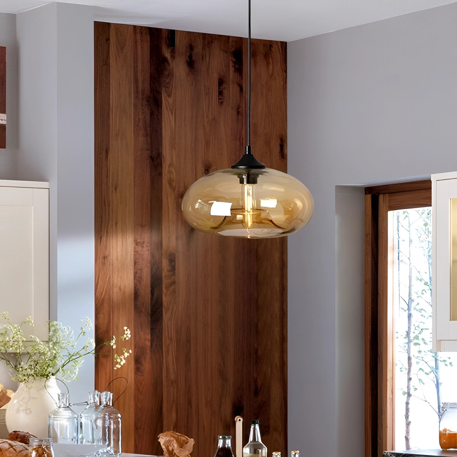 Colorful glass pendant lights in a modern mid-century ceiling fixture design, suspended from a wooden ceiling and illuminating a stylish interior setting with wood and neutral tones.
