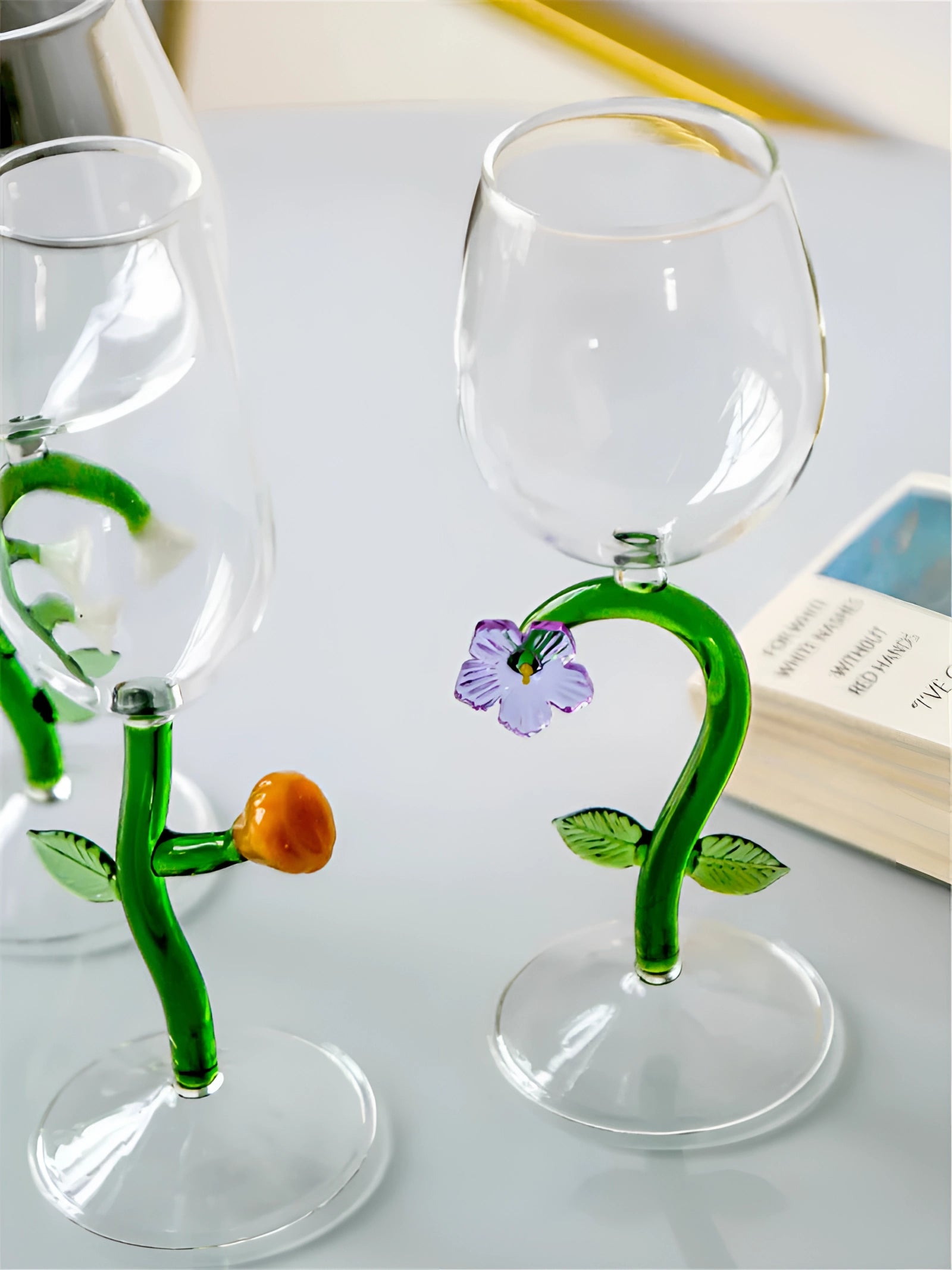 A set of decorative artistic handcrafted vineyard wine glasses featuring green and yellow designs, displayed with fluid inside.