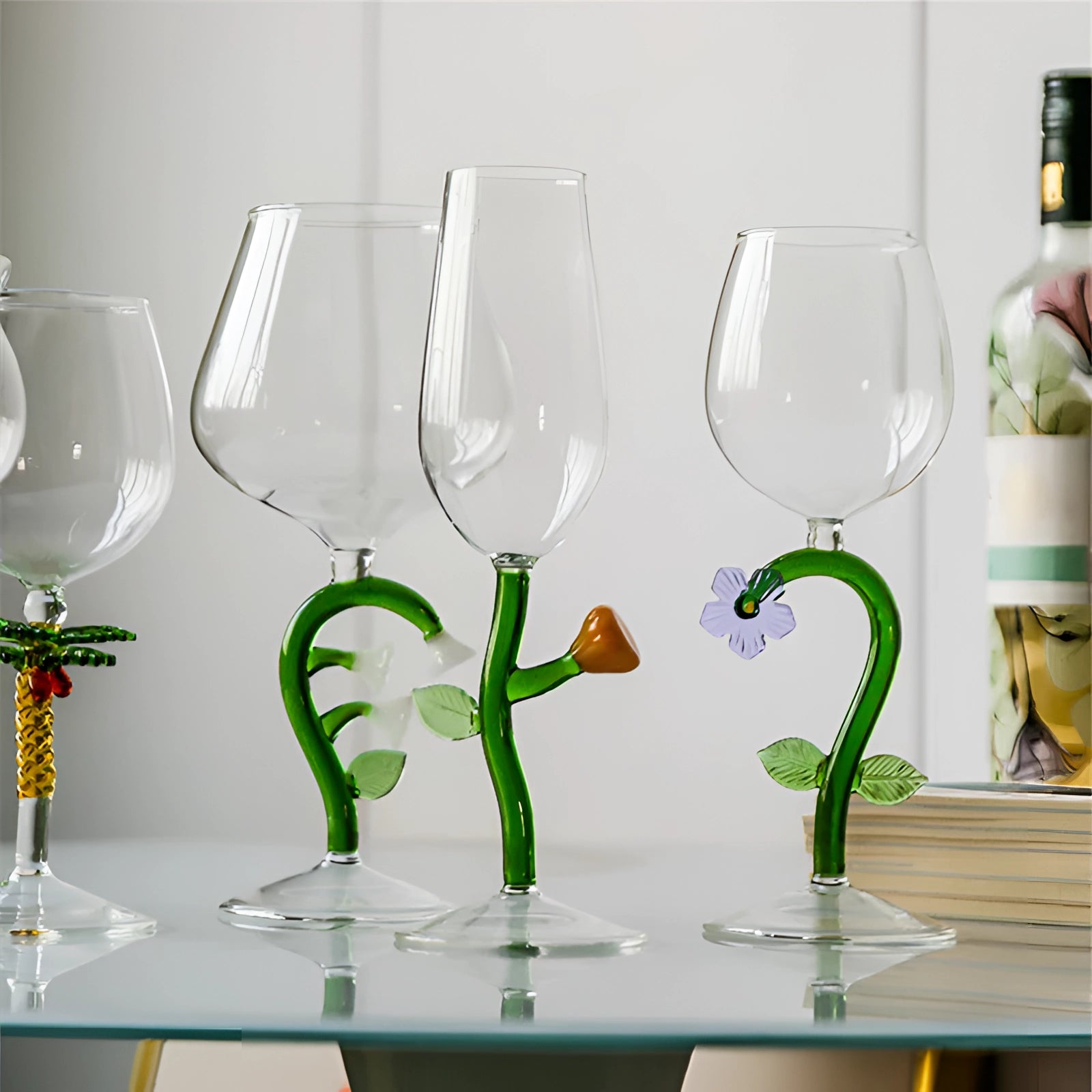 A set of decorative artistic handcrafted vineyard wine glasses filled with white wine, surrounded by green and yellow plants, under bright lighting, suitable for interior design and barware settings.