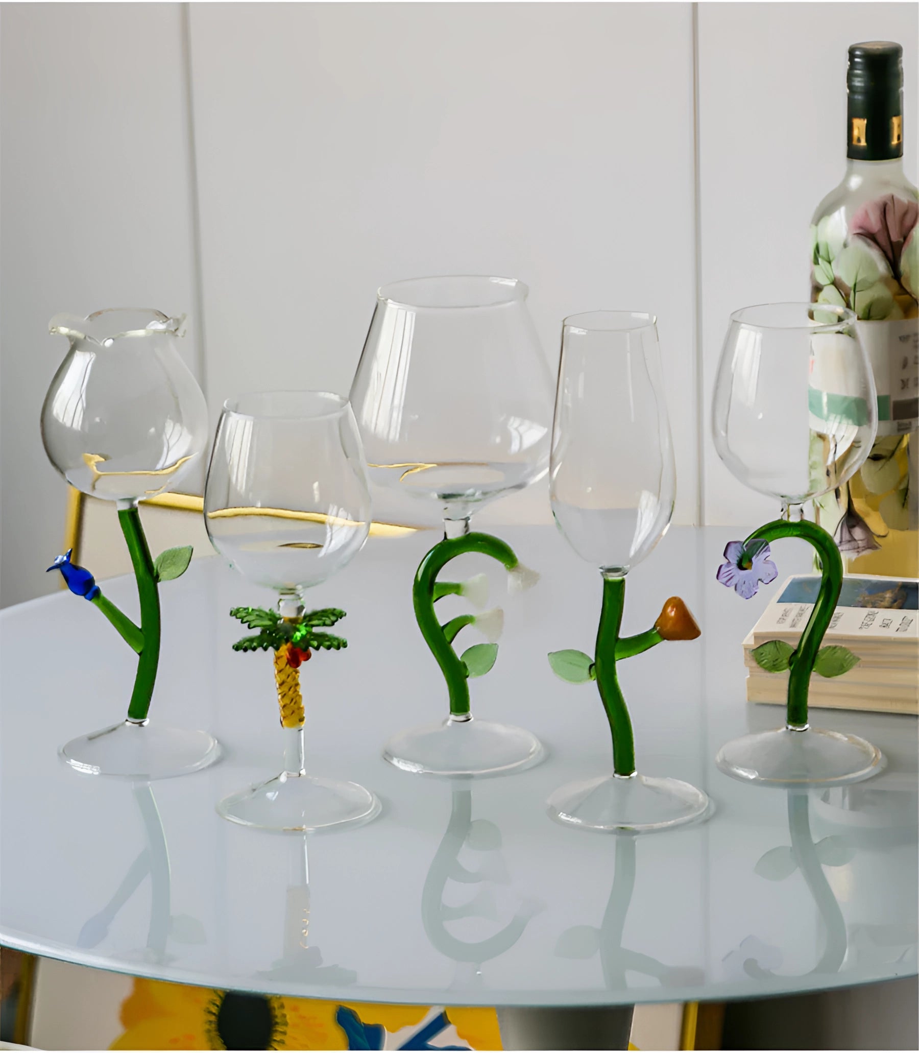 A set of decorative, artistic, handcrafted vineyard wine glasses displayed on a table with white and green accents, showcasing intricate stemware design.
