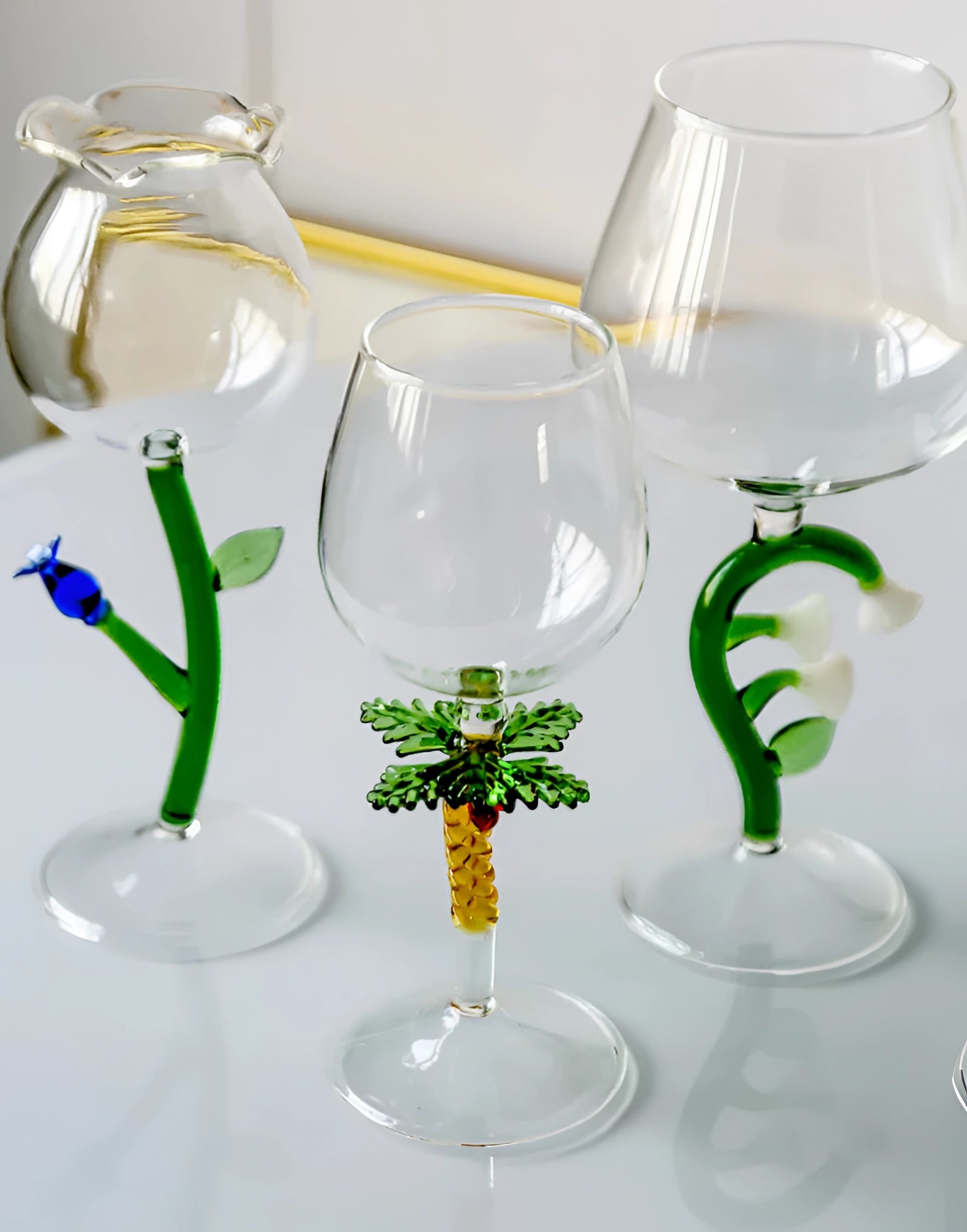 Set of decorative artistic handcrafted vineyard wine glasses, green glass with plant motifs, displayed as drinkware and tableware.