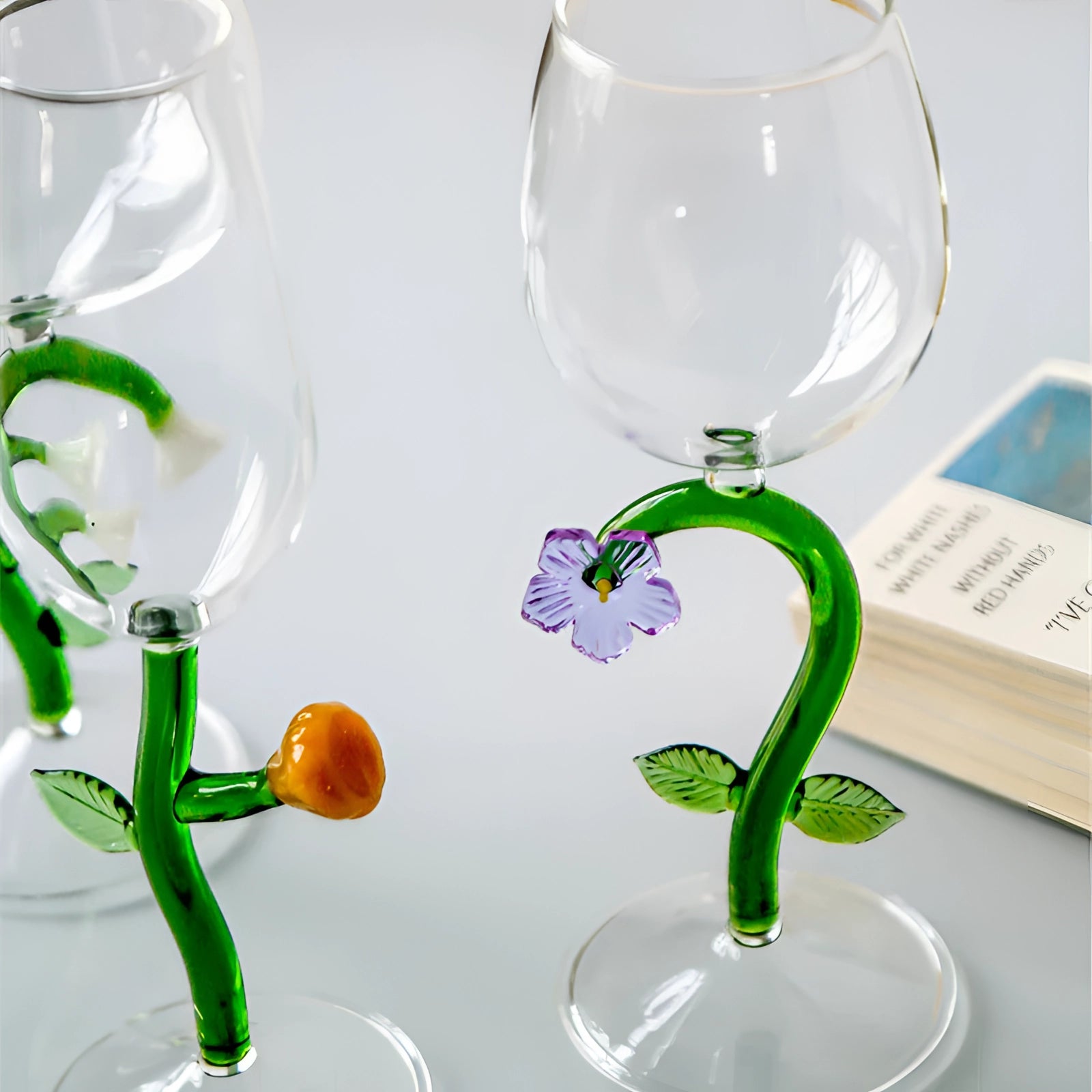 A set of decorative handcrafted vineyard wine glasses filled with white wine against a green backdrop.