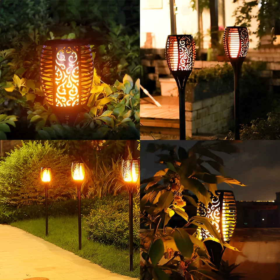 Decorative LED Solar Flame Torches illuminating a garden at night with lush green plants in the background.