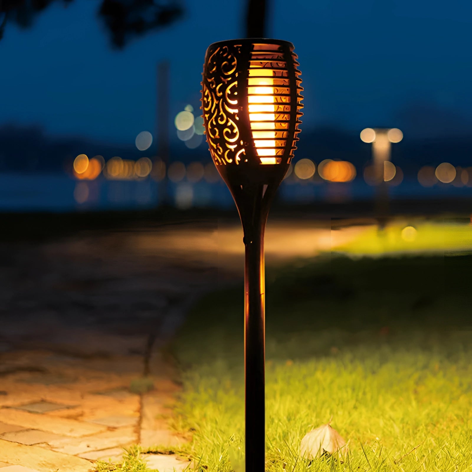 Decorative LED Solar Flame Torches illuminating a garden with vibrant, flickering light; waterproof design suitable for outdoor use, surrounded by grass and plants.