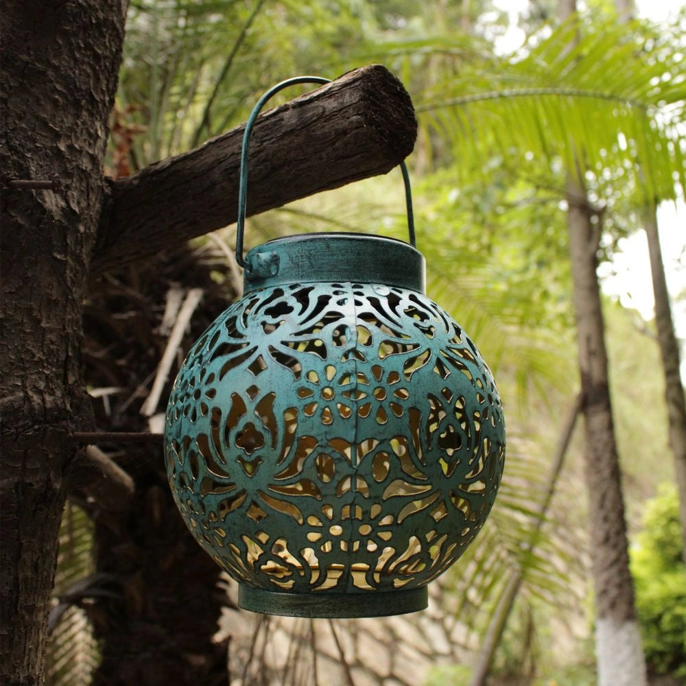 Decorative solar lantern with a floral cut-out design, projecting intricate shadows onto surrounding surfaces.