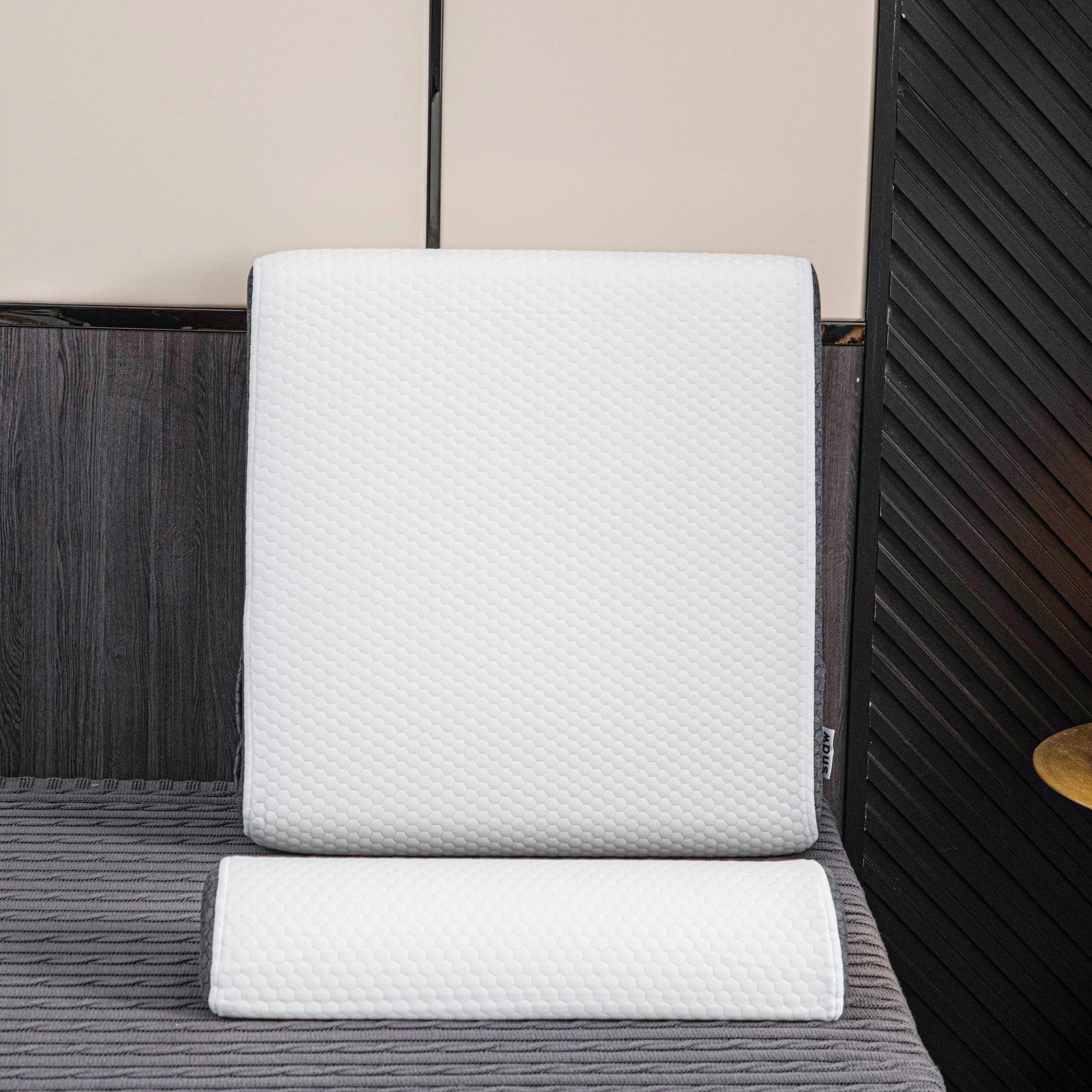 Ergonomic memory foam neck support pillow with a rectangular shape, designed for comfort and adjustability, resting on a wooden floor.