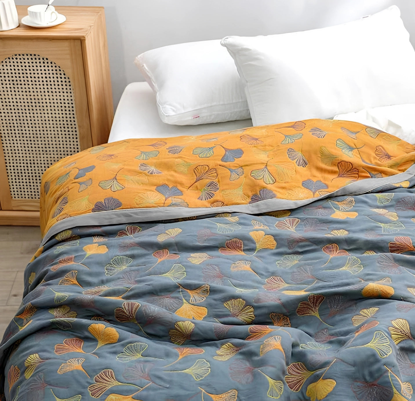 Ginkgo leaf pattern duvet cover in yellow and gray tones on a neatly made bed, surrounded by coordinating pillows in a cozy bedroom setting.