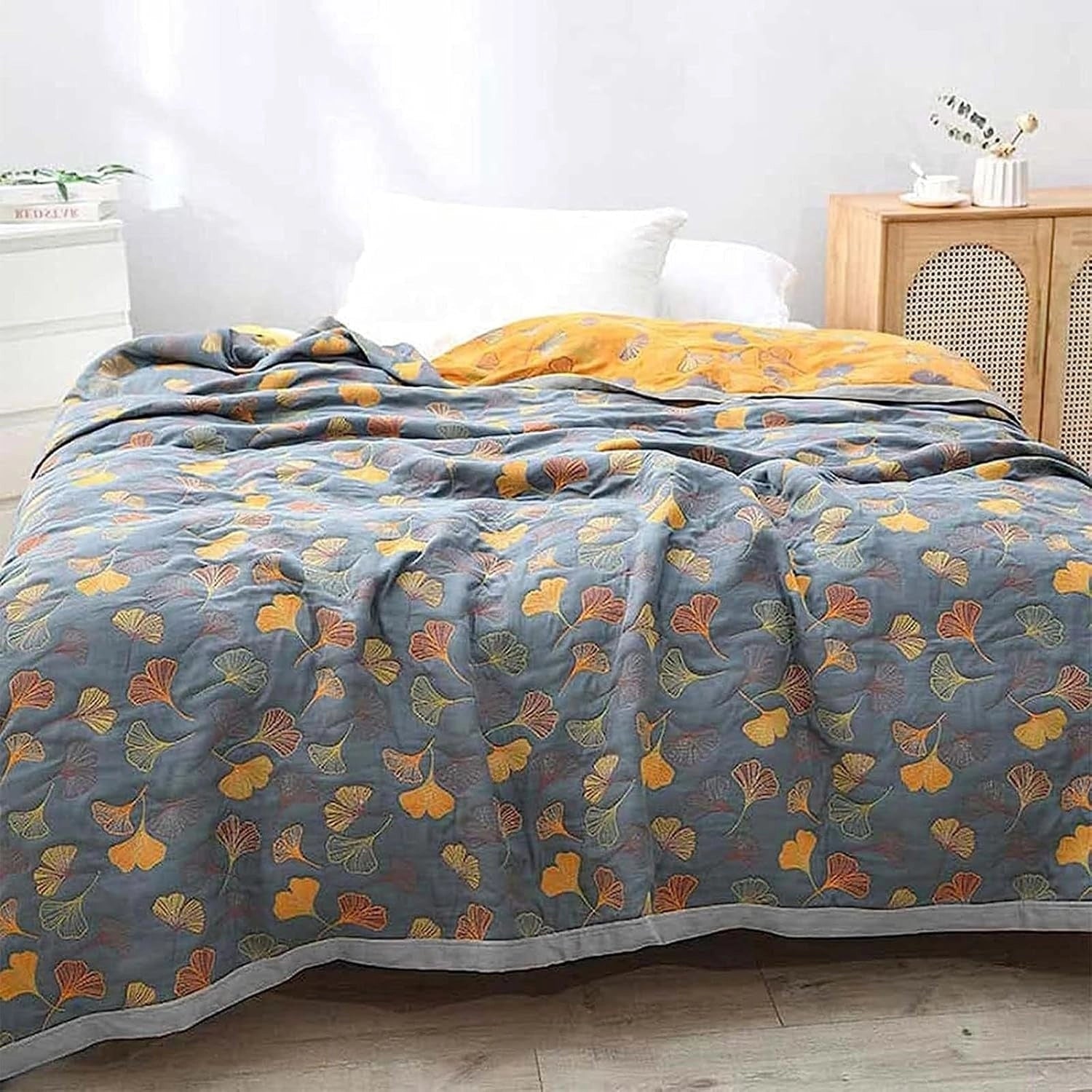 Yellow and gray duvet cover with a ginkgo leaf pattern on a bed with a wooden bed frame; the room features a wooden floor, adding a warm, autumnal feel to the decor.