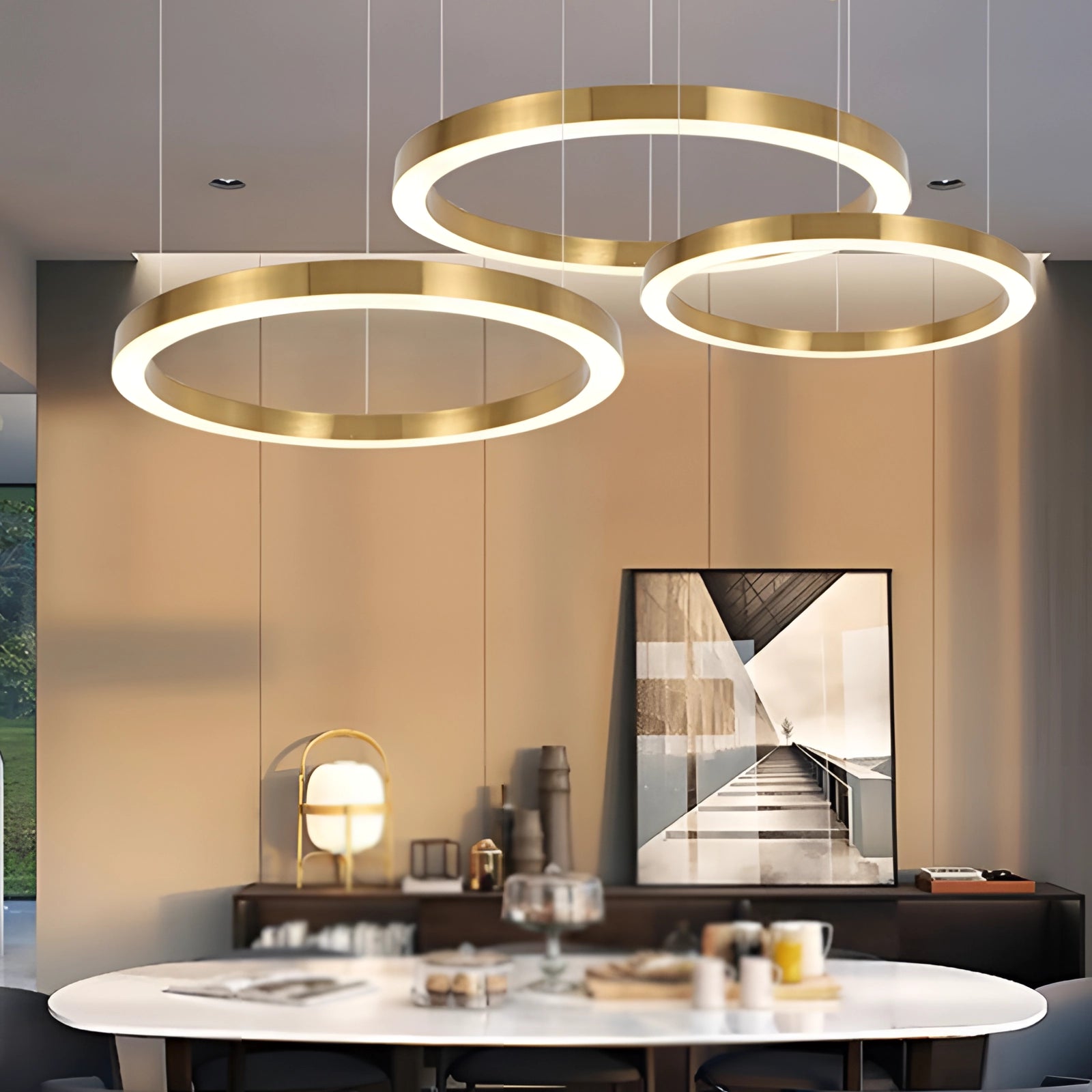 Gold circular LED chandelier hanging from a ceiling in a modern minimalist interior setting, featuring elements such as a wooden table, couch, and mirror, with a focus on the sleek and stylish design of the light fixture.