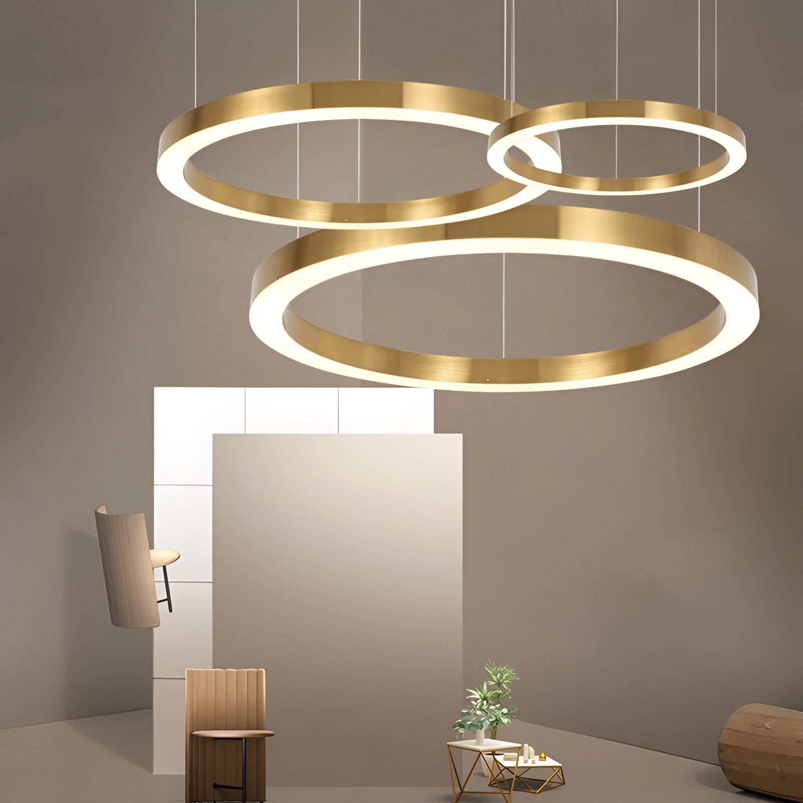 Gold Circular LED Chandelier hanging in a modern minimalist interior, emitting a warm yellow light against a wood-accented wall.