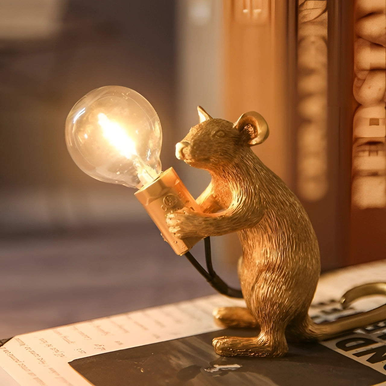 Quirky gold mouse-shaped desk lamp with a sitting posture, featuring detailed sculptural elements and a metallic finish, ideal for eccentric decor.