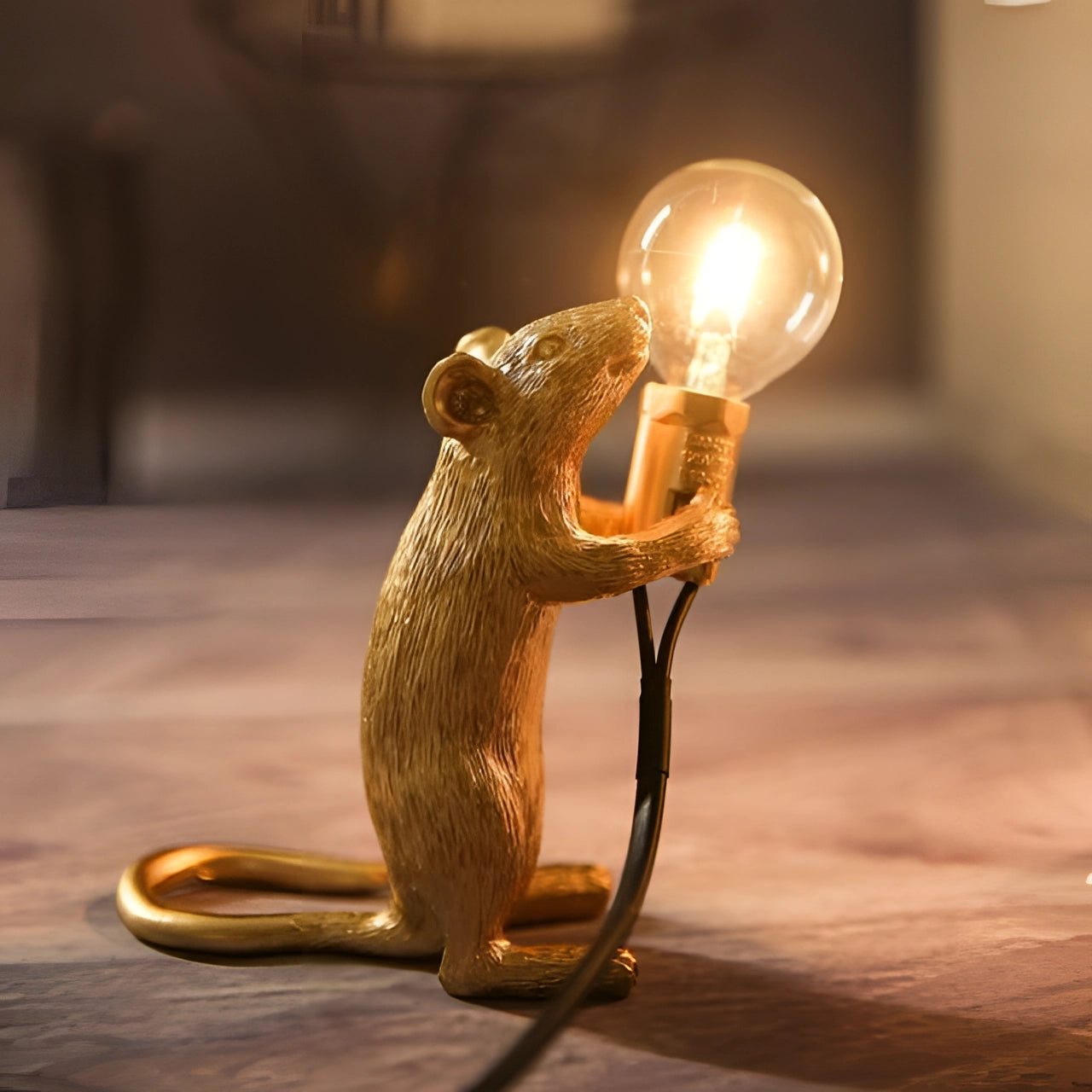 Gold standing mouse-shaped lamp with a metallic finish, featuring a quirky design and holding a light bulb, suitable for adding an eccentric touch to desk decor.