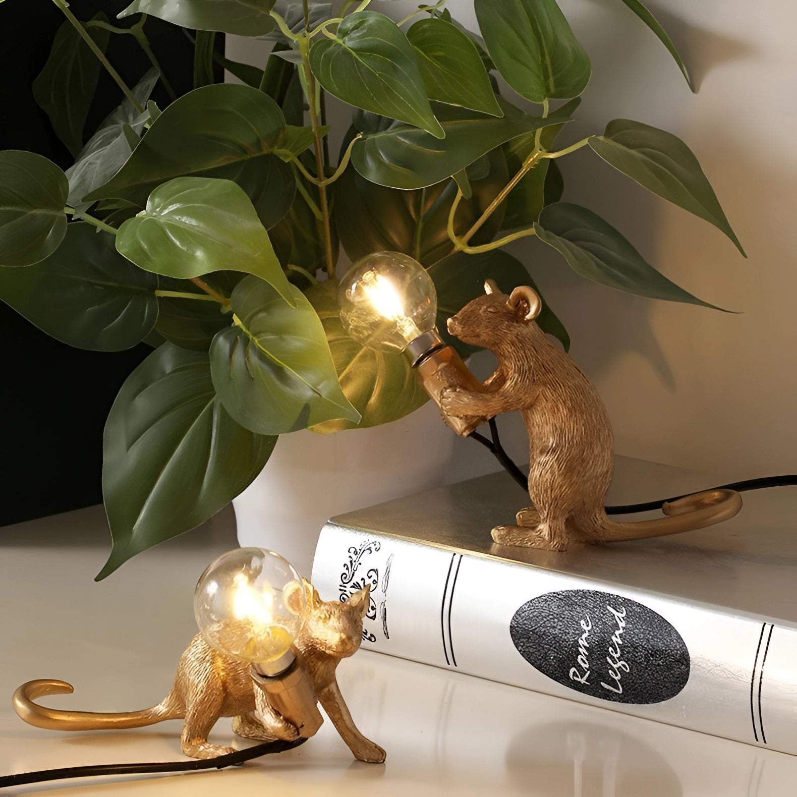 Gold mouse-shaped desk lamp with a quirky and eccentric design, placed on a table surrounded by houseplants.