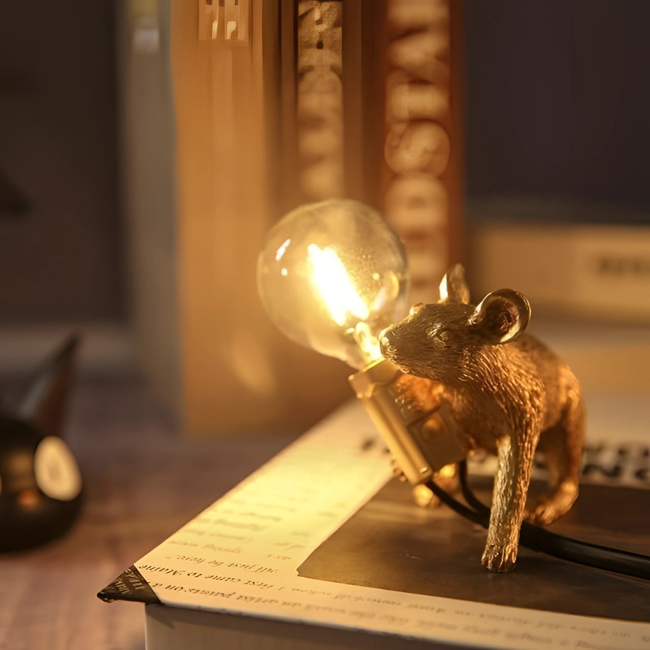 A quirky gold mouse-shaped desk lamp with a squat posture, featuring a metallic finish and serving as an eccentric decor piece.