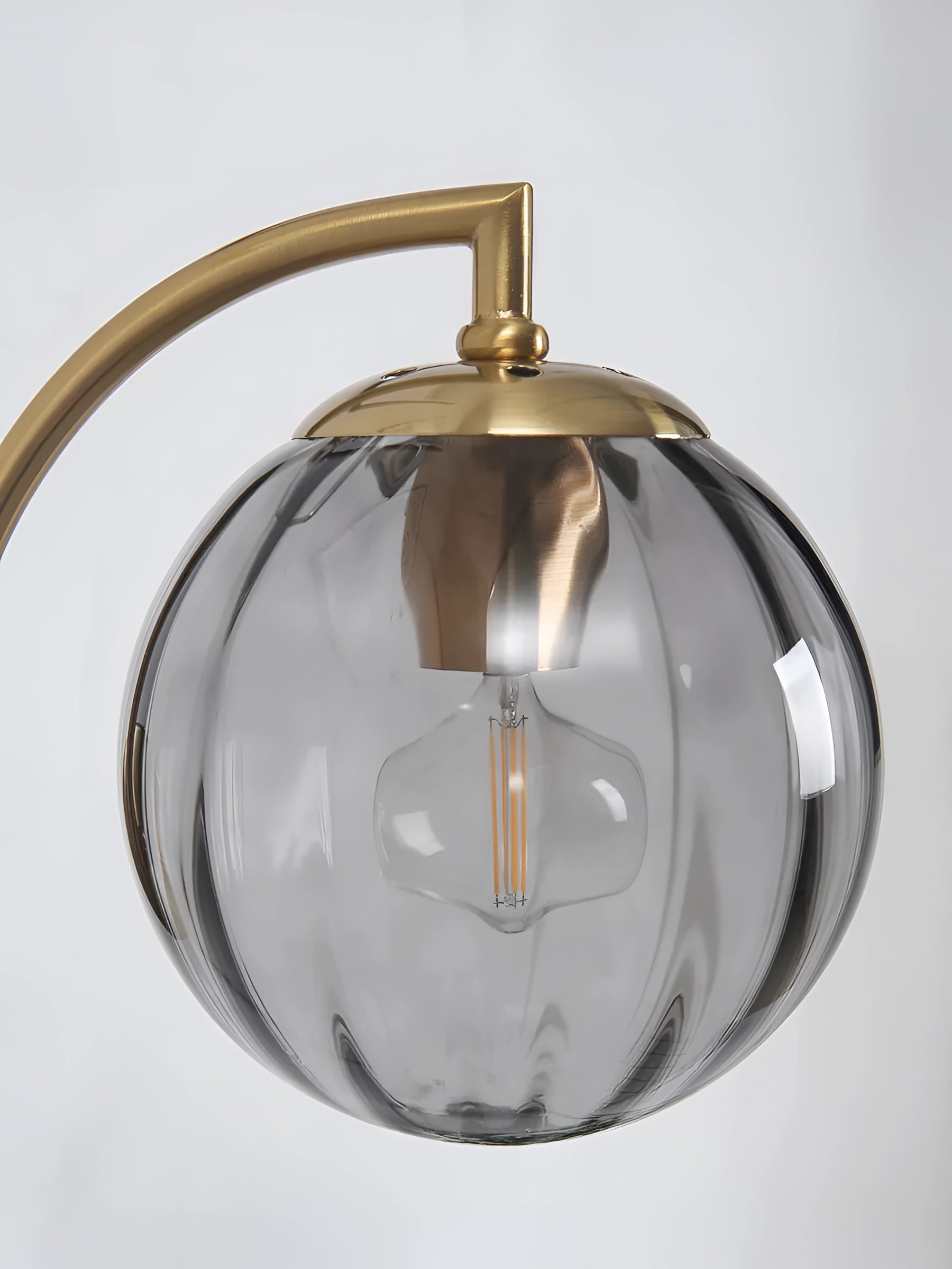 Modern gold wall sconce with a ribbed glass globe, brass finish, mounted on a wall.