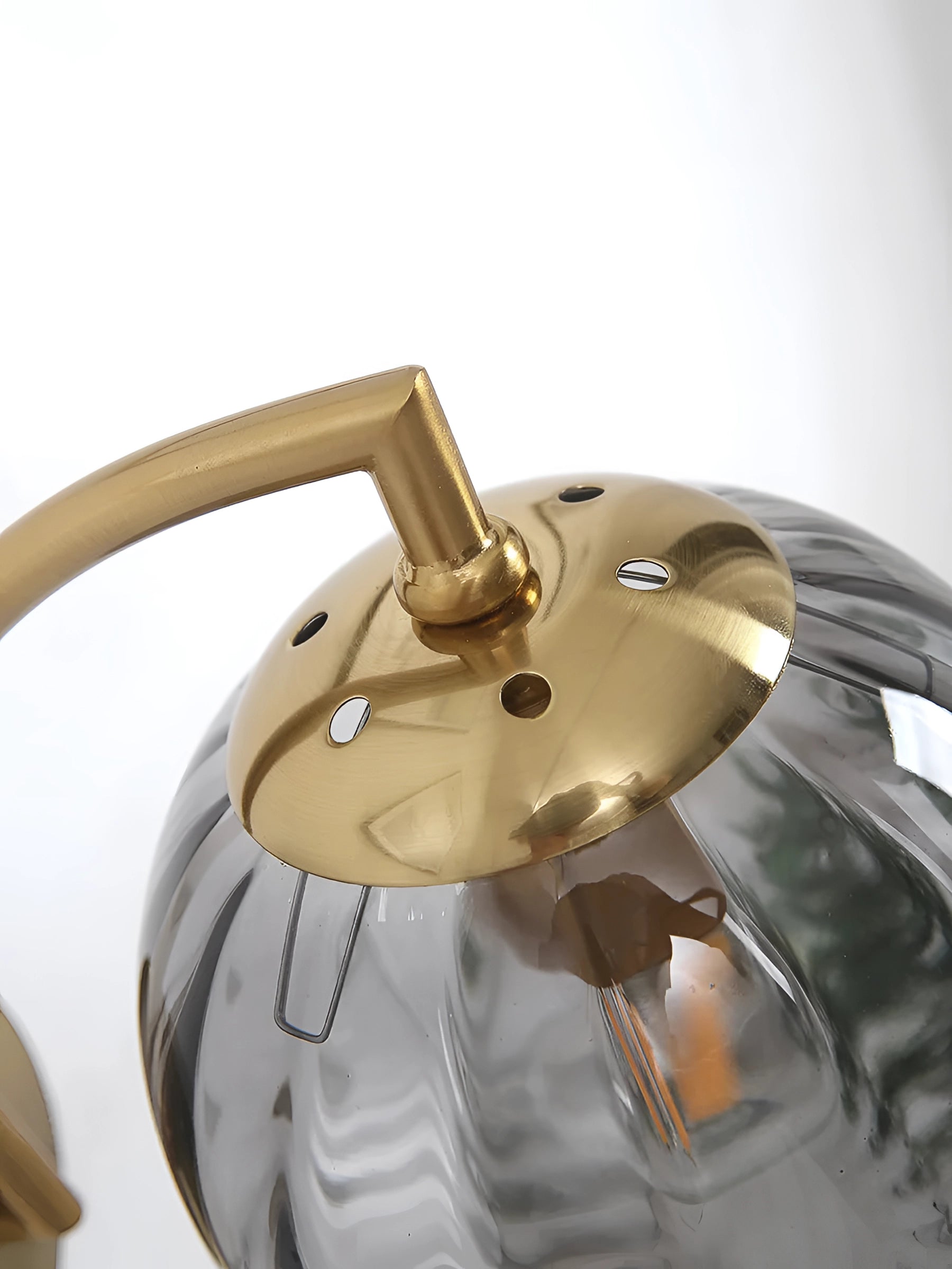 Modern brass gold wall sconce with ribbed glass globe mounted on wall.