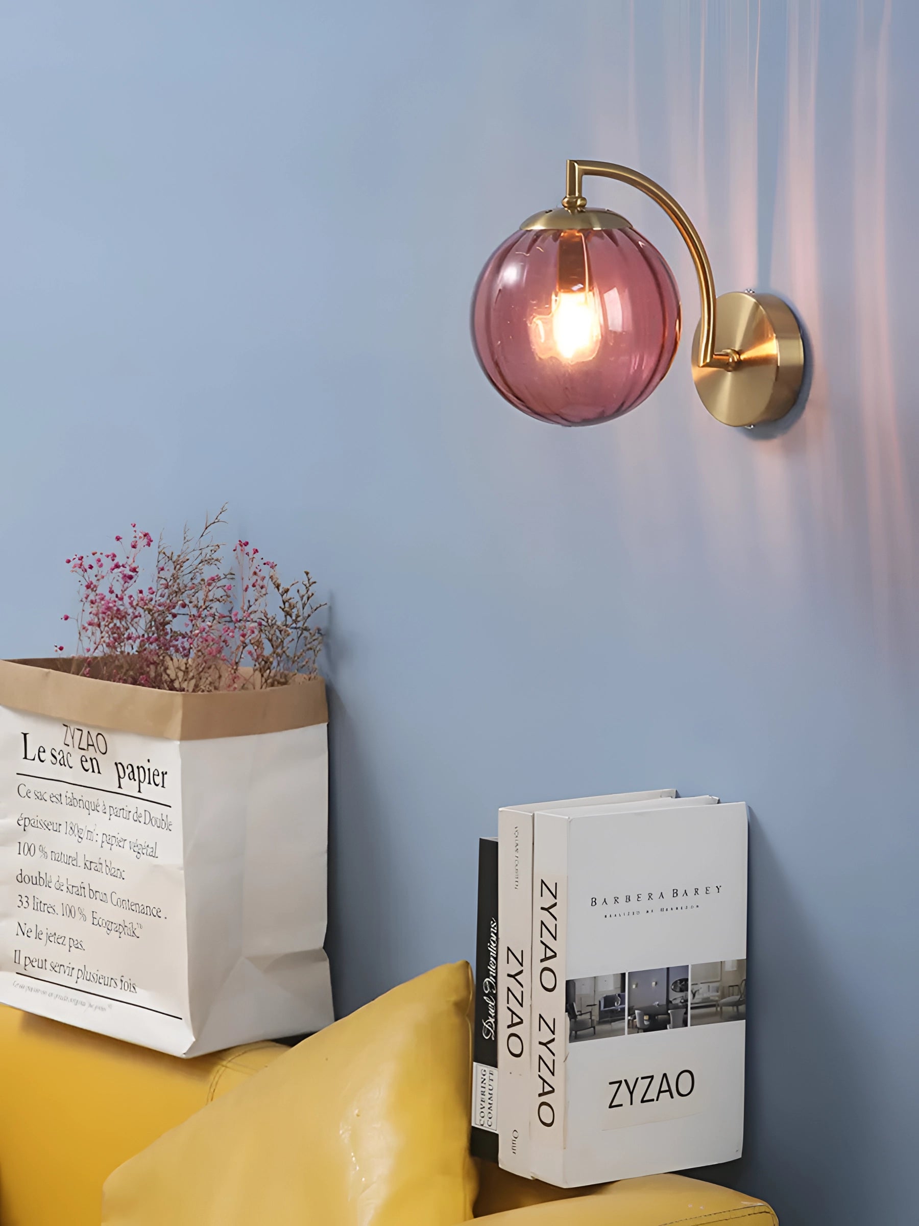A modern gold wall sconce with a ribbed glass globe, mounted on a brass fixture, illuminating a room with warm yellow light.
