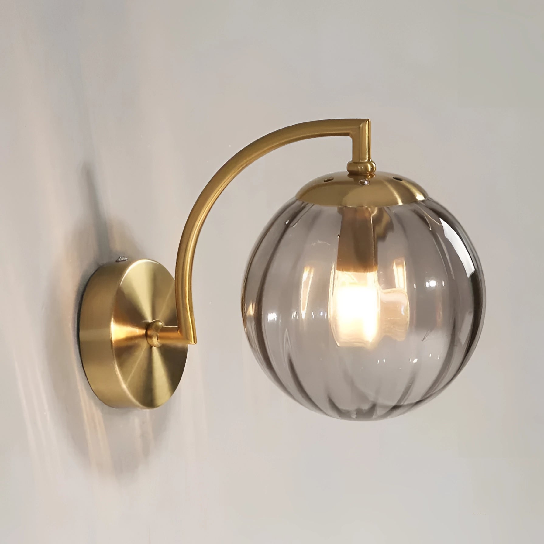 Gold Wall Sconce with Ribbed Glass Globe in Smoky Gray finish, featuring a modern brass wall lamp design with a circular ribbed glass shade.