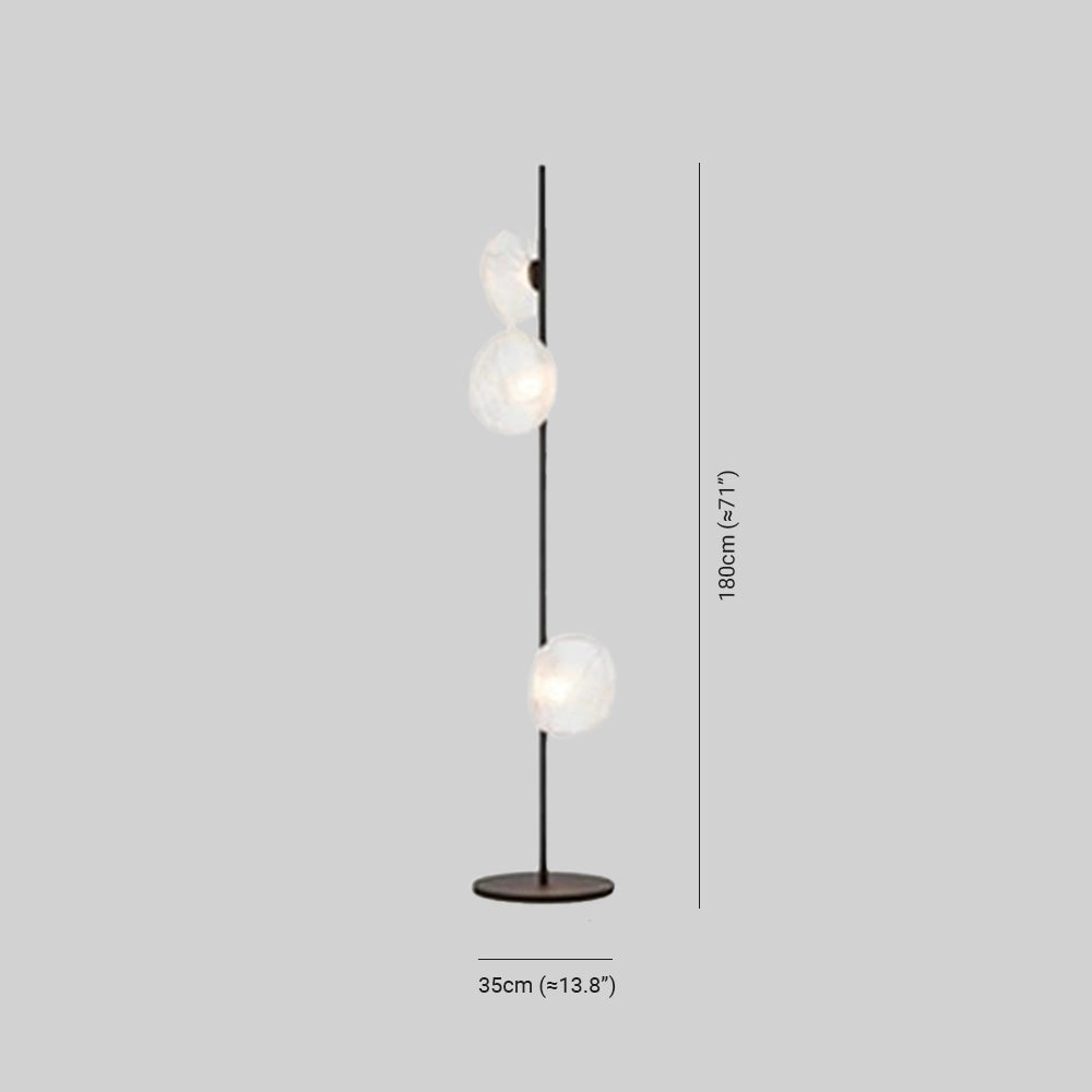Industrial metallic pebble floor lamp with sculptural design, featuring a textured metallic finish and an artistic arrangement of circular and rectangular elements, illuminating a room with its unique designer style.