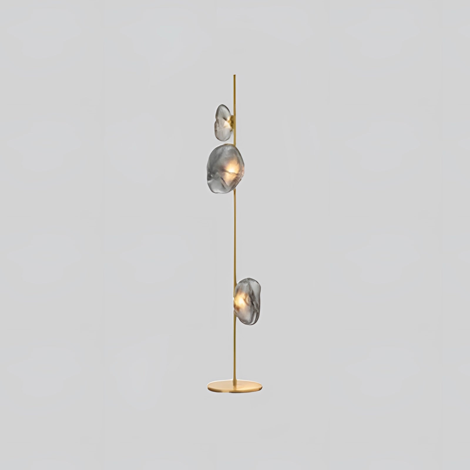 Industrial metallic pebble floor lamp featuring a sculptural design with three spherical heads in gold and smoke gray, set against a modern and artistic setting.