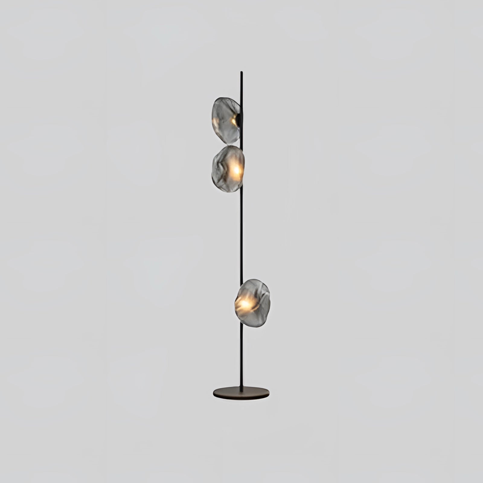 Industrial metallic pebble floor lamp with a sculptural design, featuring three heads in black and smoke gray. The lamp showcases a modern aesthetic with metal accents and resembles a contemporary street light with its circular and ceiling fixture-like elements.