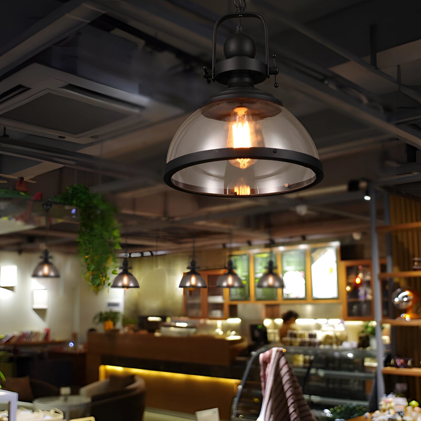 Industrial pendant lights with Edison bulbs hanging from the ceiling in a rustic interior setting, featuring a cozy room with a couch, coffee table, and houseplants.