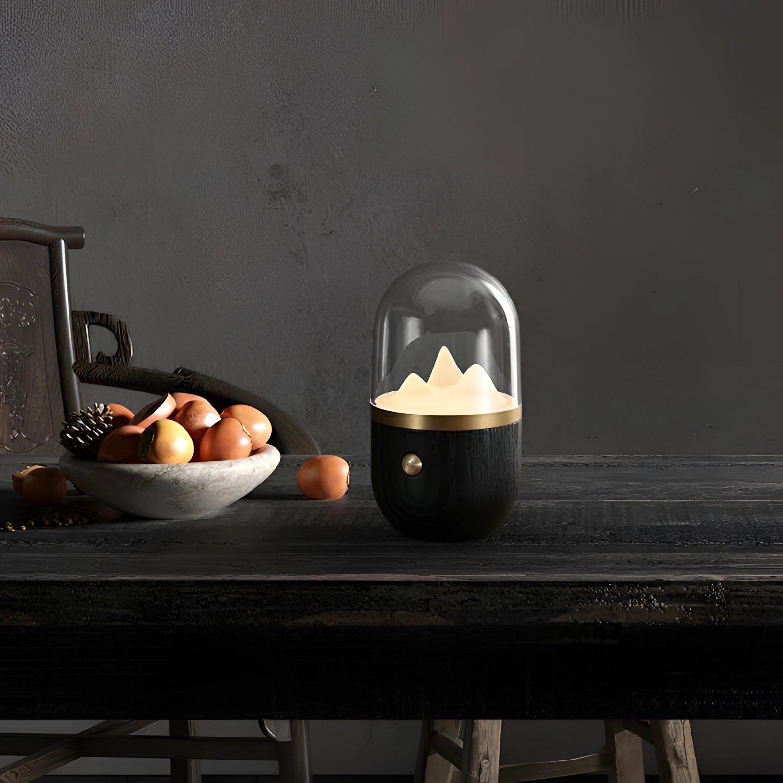 LED flame lamp on a wooden base, placed on a table with black accents and surrounded by tableware and fruit.